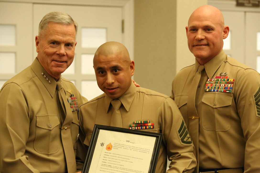 Commandant of the Marine Corps Gen. James Amos and Sgt. Maj. of the Marine Corps Micheal Barrett pose with Staff Sgt. Victor Perez at The Clubs of Quantico on Feb. 3, 2014. Staff Sgt. Perez was meritoriously promoted to gunnery sergeant due to his outstanding performance as a prior service recruiter in 2013.