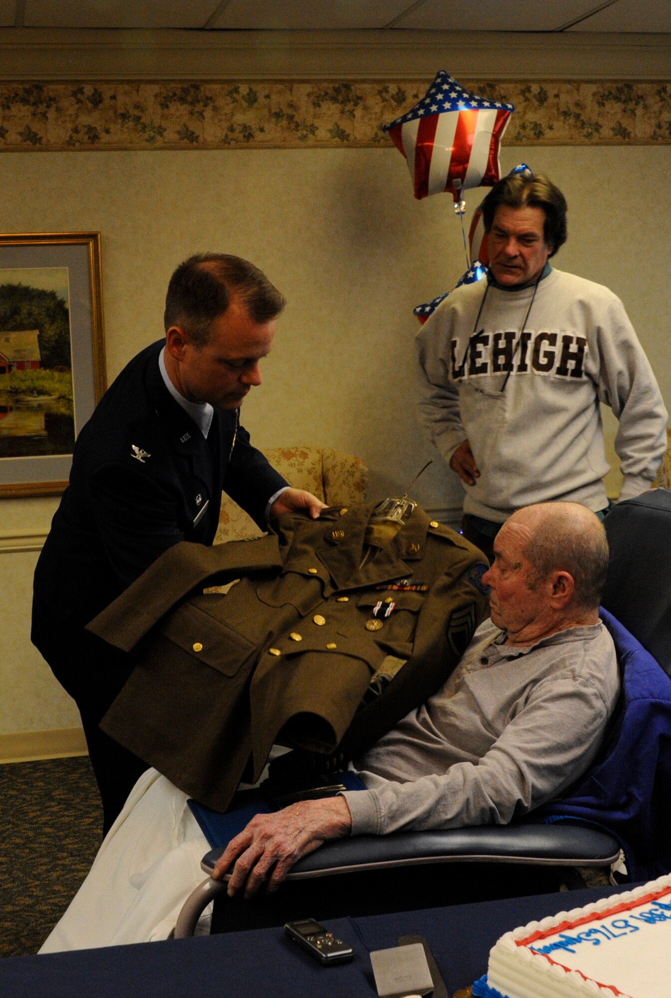 Air Force Col. James C. Hodges, Joint Base McGuire-Dix-Lakehurst and 87th Air Base Wing commander, displays former Army Air Force Staff Sgt. Kenneth E. Yousts’ (center) uniform during a Prisoner of War Medal presentation Jan. 27, 2014, at the Schuylkill Center Nursing Home, Pottsville, Pa. The POW medal was presented to Youst seven decades later after his internment in a Swiss prison during World War II. (U.S. Air Force photo by Pascual Flores) 