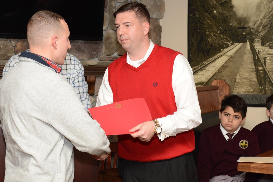Maj. Charles O’Neill, inspector-instructor for Delta Co., 4th Light Armored Reconnaissance Battalion, presents a commanders award to Sgt. Igor Dunayevskiy at Brock’s Riverside Bar and Grill during the annual Toys for Tots Luncheon on Jan. 28, 2014, for his volunteer service during the 2013 Toys for Tots campaign.