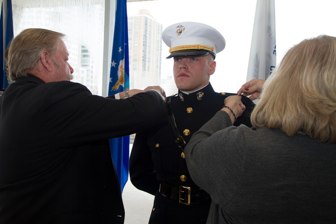 Mr. and Mrs. Hillebrand pin the rank of Second Lieutenant on their son, Justin Hillebrand, during his commissioning ceremony at the Milwaukee County War Memorial Center, Jan. 24, 2014.