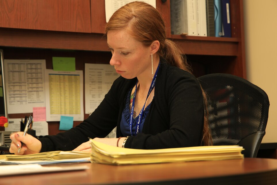 Audrey Mickelson, client service assistant, Navy Marine Corps Relief Society, looks over receipts for quick assist loans to make sure all the information is accurate Feb. 3 at the Village Center Office. The NMCRS offers counseling for young Marines on finances and money management.