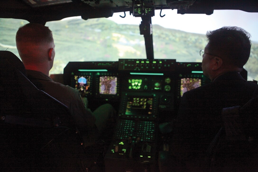 Maj. John P. Arnold (left) teaches Toshihiko Matsumoto how the controls of an MV-22B Osprey tiltrotor aircraft work in a flight simulator Jan. 28 during a visit by Japan defense officials to Marine Corps Air Station Futenma. The simulator allowed the visiting officials to see the importance of the aircraft and the level of training the pilots undergo. Matsumoto is the deputy director general with the Okinawa Defense Bureau, and Arnold is the current operations officer with Marine Aircraft Group 36, 1st Marine Aircraft Wing, III Marine Expeditionary Force. Photo by Cpl. Anne K. Henry 