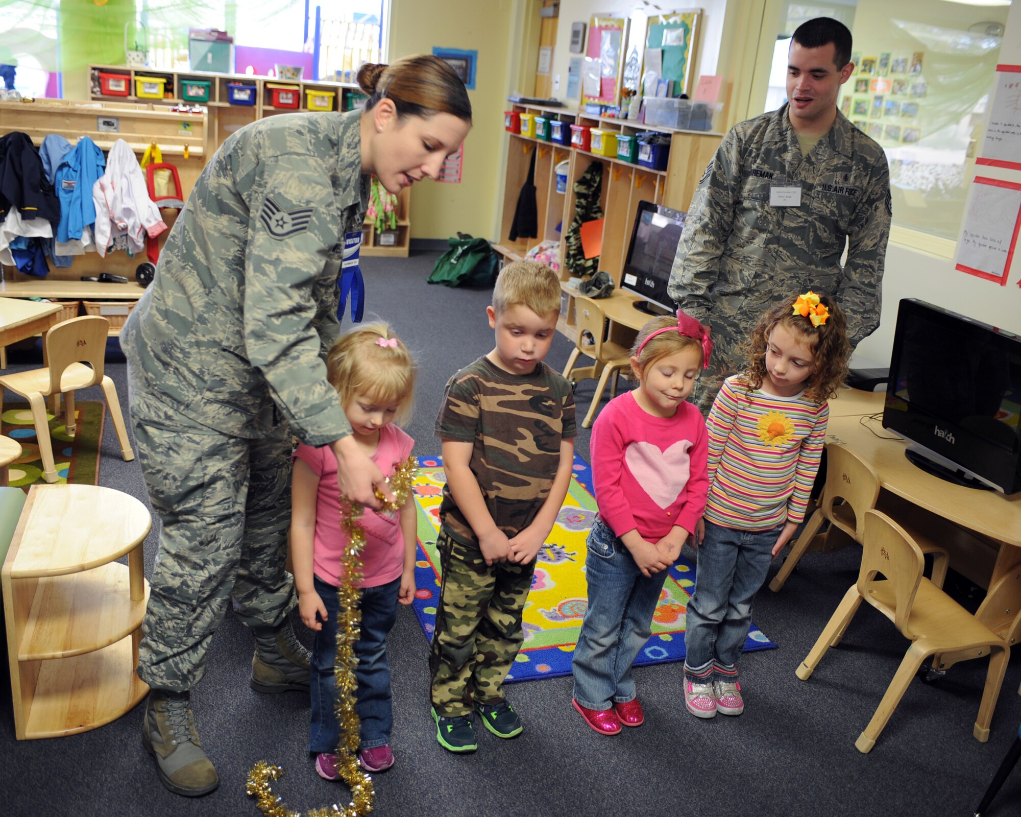 U.S. Air Force Staff Sgt.'s Kristy Stowell and Kyle Wireman, 355th Dental Squadron dental technicians, simulate the proper way to floss teeth by using garland as dental floss and children as teeth during a presentation at the D-M Child Development Center at Davis-Monthan Air Force Base, Ariz., Feb. 3, 2014.  To observe National Children's Dental Health Month, the dental professionals gave short presentations to the children on brushing and flossing techniques, talked about healthy eating to prevent cavities and gum disease, and stressed the importance of visiting the dentist on a regular basis.  (U.S. Air Force photo by Airman 1st Class Chris Massey)