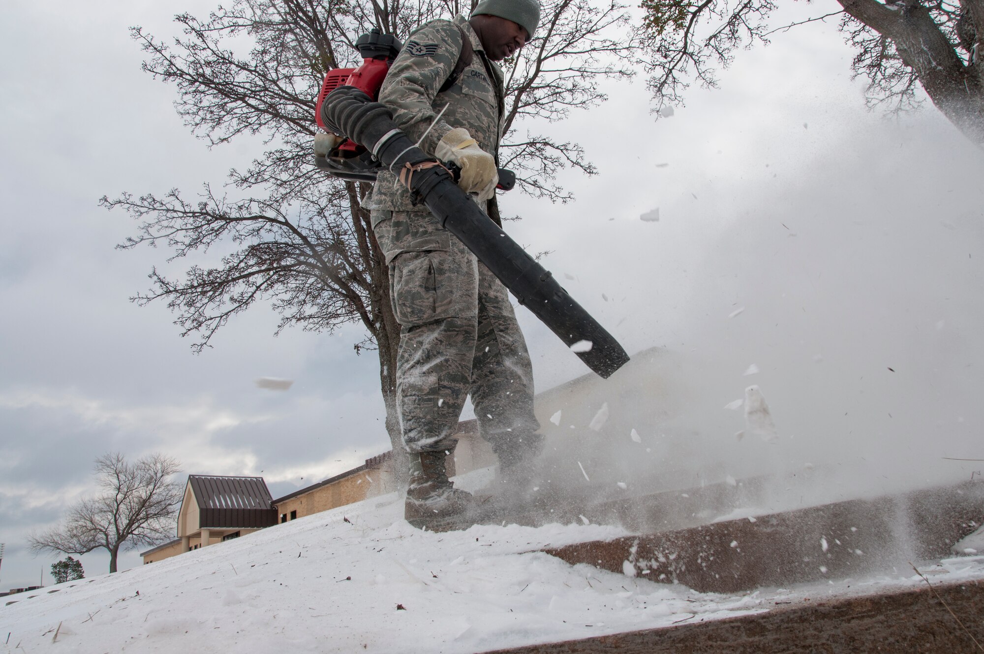 Staff Sgt. Erik Cartwright uses a leaf blower to remove snow from the steep steps between the 507th Air Refueling Wing headquarters building and the 507th Logistics Readiness Squadron.  The storm moved into the central Oklahoma area Thursday Feb. 6, 2014, dumping nearly three inches of light powdery snow on Tinker AFB.  Members of the 507th spent limited time getting areas cleared up as wind chills were minus 15.  (U.S. Air Force photo/Senior Airman Mark Hybers)