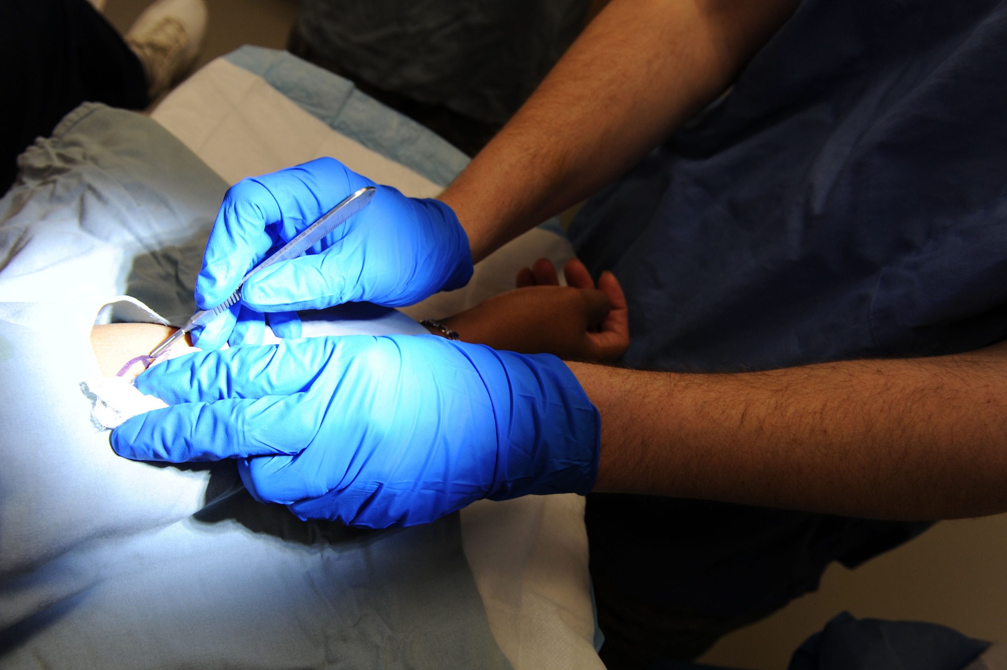 U.S. Air Force Maj. Jason Boyd, 633rd Medical Operations Squadron chief of dermatology, performs a routine skin tag removal surgery at Langley Air Force Base, Va., Feb. 4, 2014. Even though the Dermatology clinic can assist with a variety of conditions, their main goal is to diagnose and treat skin cancer. Boyd is a native of Tacoma, Texas. (U.S. Air Force photo by Senior Airman Brittany Paerschke-O’Brien/Released)