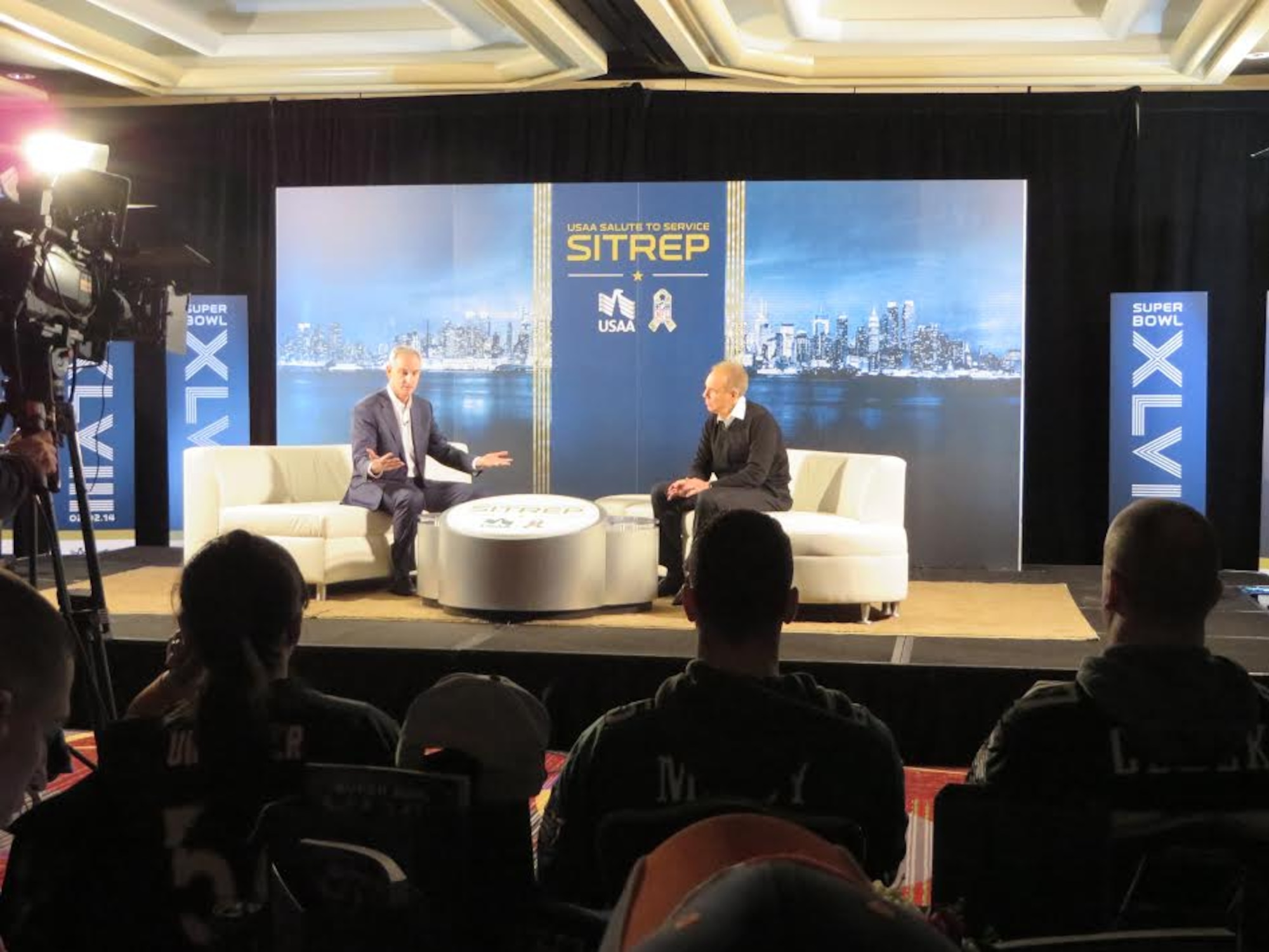Service members and their guests wear their favorite NFL team jerseys during the USAA Salute to Service SITREP show Feb. 1, 2014, in the NFL House in Manhattan, N.Y. The host of the show, Trey Wingo, interviews hall of fame quarterback (Dallas Cowboys) Roger Staubach and discusses his football career and military affiliation. Attendees were invited by USAA to partake in the Super Bowl festivities in New York City, which included meeting NFL celebrities and a catered lunch. (U.S. Air Force photo by 2nd. Lt. Carrie Volpe/Released)