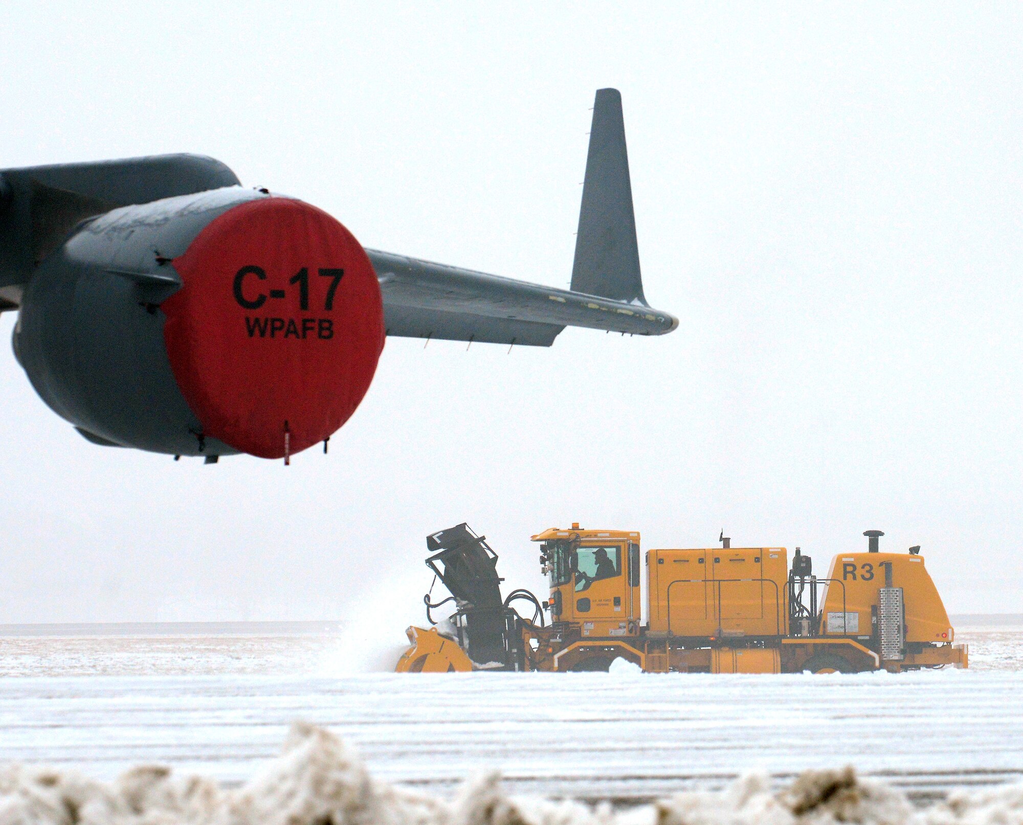 WRIGHT-PATTERSON AIR FORCE BASE, Ohio - Snow surrounding a 445th Airlift Wing C-17 Globemaster III sitting on the ramp is removed as temperatures drop and fog rolls in at Wright Patterson Air Force Base, Ohio, Jan. 10, 2014. A winter storm brought several inches of snow and record low temperatures to the area at the beginning of the new year. Another significant amount of snow and ice fell in the area Feb. 5. (U.S. Air Force photo/Tech. Sgt. Frank Oliver) 