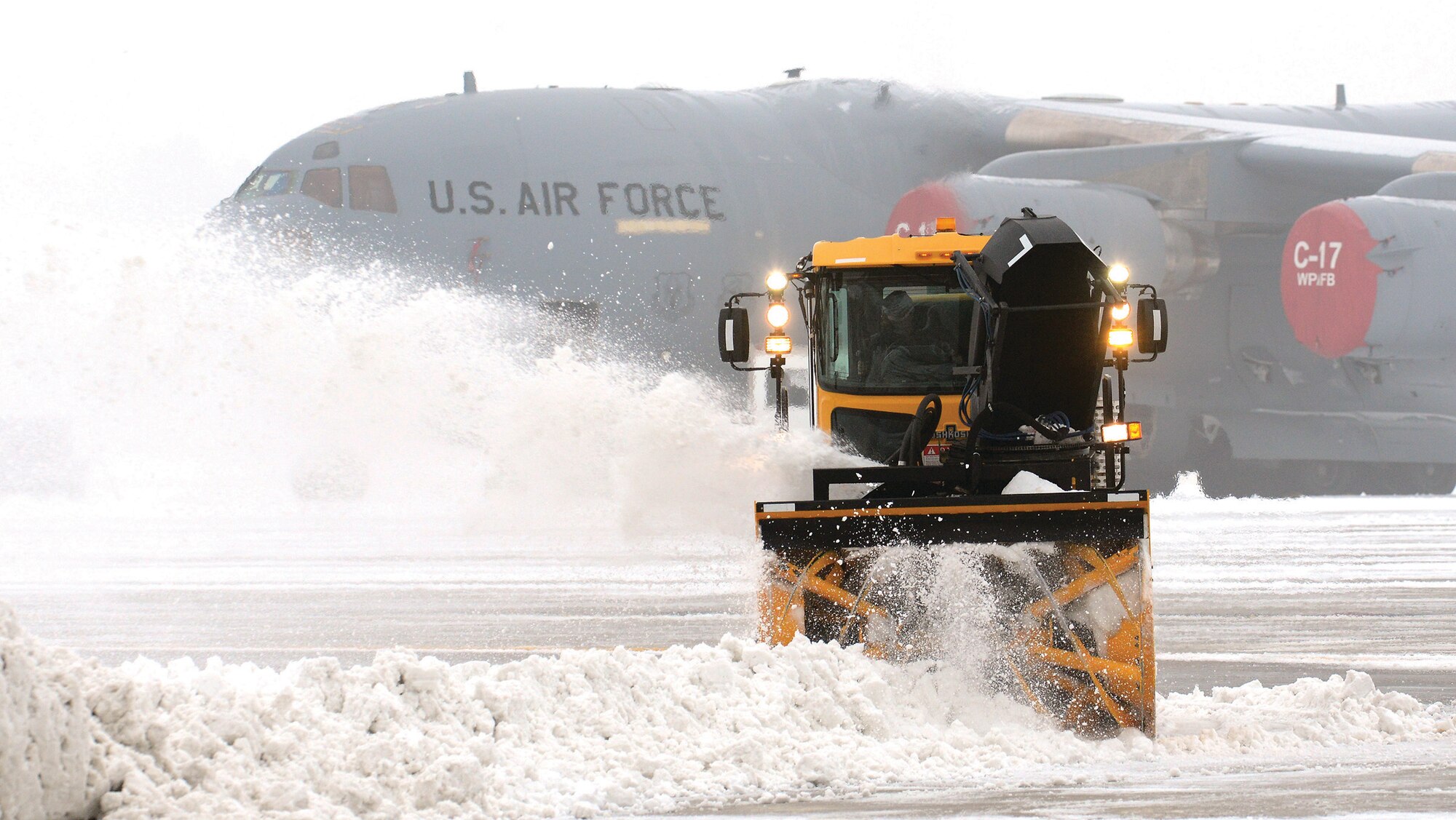 WRIGHT-PATTERSON AIR FORCE BASE, Ohio - Snow surrounding a 445th Airlift Wing C-17 Globemaster III sitting on the ramp is removed as temperatures drop and fog rolls in at Wright Patterson Air Force Base, Ohio, Jan. 10, 2014. A winter storm brought several inches of snow and record low temperatures to the area at the beginning of the new year. Another significant amount of snow and ice fell in the area Feb. 5. (U.S. Air Force photo/Tech. Sgt. Frank Oliver) 