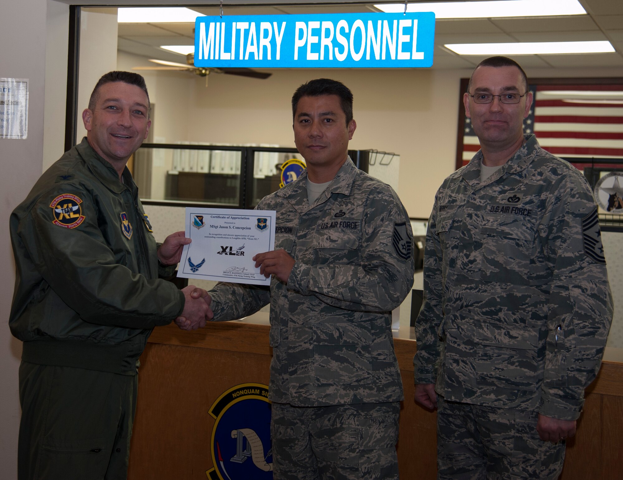 Master Sgt. Jason Concepcion, center, 47th Force Support Squadron Manpower Operations superintendent, poses with Col. Brian Hastings, left, 47th Flying Training Wing commander, and Chief Master Sgt. Garry Berry, 47th FTW command chief, after being presented the XLer of the week award here Jan. 29, 2014. The XLer is a weekly award chosen by wing leadership and given to those who consistently make outstanding contributions to Laughlin and their unit. (U.S. Air Force photo/Airman 1st Class Jimmie D. Pike)