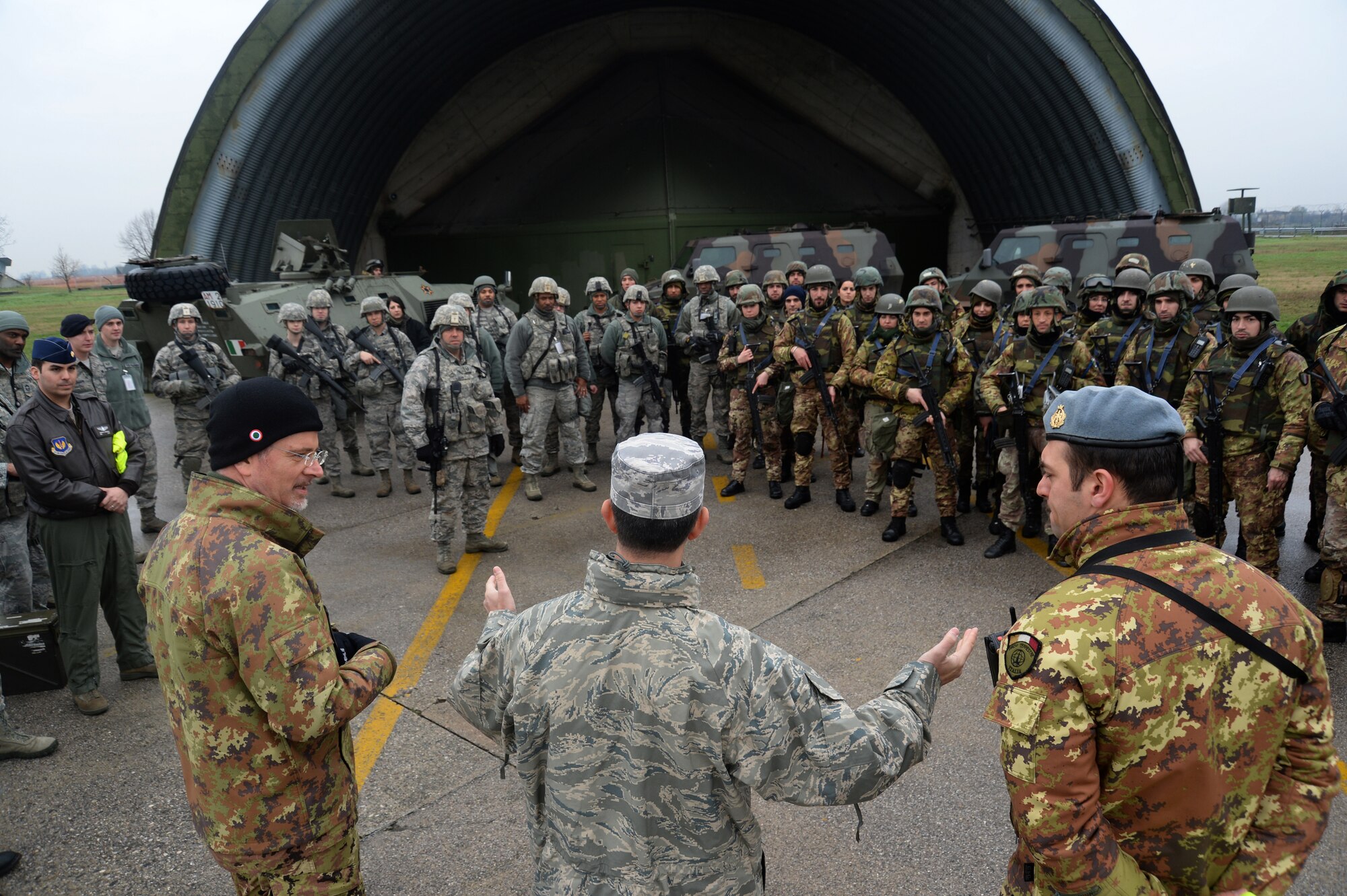 U.S. Air Force Col. David Julazadeh, commander of 52nd Fighter Wing, center, speaks to Italian and American Airmen after the completion of a joint training exercise at Ghedi Air Base, Italy, Jan. 31, 2014. The Italian and American Air Forces share a bilateral agreement as part of the NATO alliance. (U.S. Air Force photo illustration by Staff Sgt. Joe W. McFadden / Released)