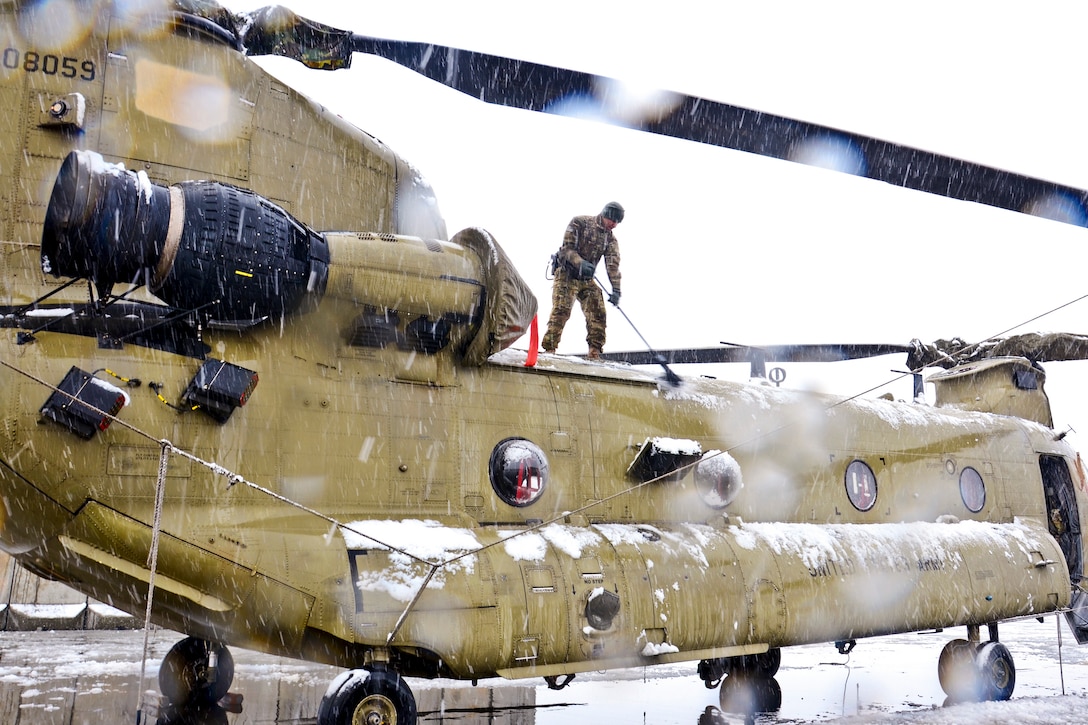 A U.S. soldier sweeps snow from a CH-47 Chinook helicopter on Bagram Airfield, Afghanistan, Feb. 6, 2013. The soldiers are assigned to the 101st Airborne Division's 159th Combat Aviation Brigade.
