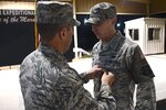 Col. John Klein Jr. awards an Air Force Achievement Medal to Staff Sgt. Kenneth Soto, 387th Expeditionary Security Forces Squadron response force leader, at an undisclosed location in Southwest Asia.