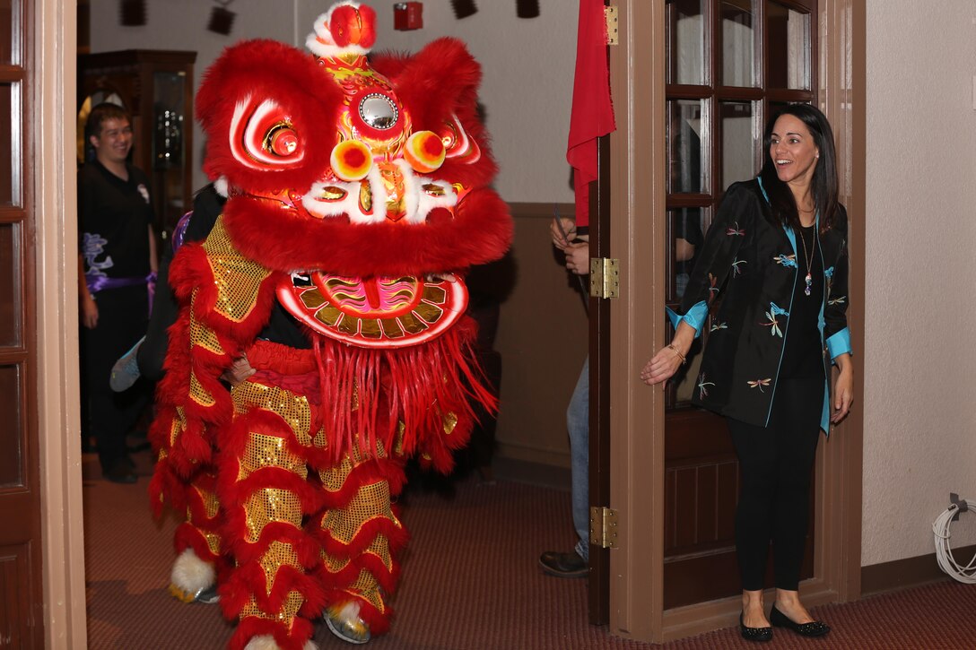 Jennifer Livingston, unit representative, Officer Spouses Club, watches as students from the University of California, Riverside, perform a Chinese lion dance during a Chinese New Year celebration at the Officers’ Club, Jan. 31. Traditional Chinese colors for the costumed lion are red, gold and green.


