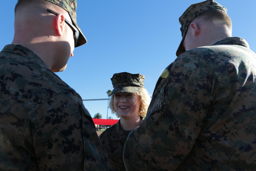 Two Marines put new corporal rank insignia on Cpl. Megan Scullin, combat videographer with 3rd Marine Aircraft Wing and a Troy, Mont., native aboard Marine Corps Air Station Miramar, Calif., Jan 6. Scullin attended the Corporals indoctrination and Corporals Course immediately following her promotion.