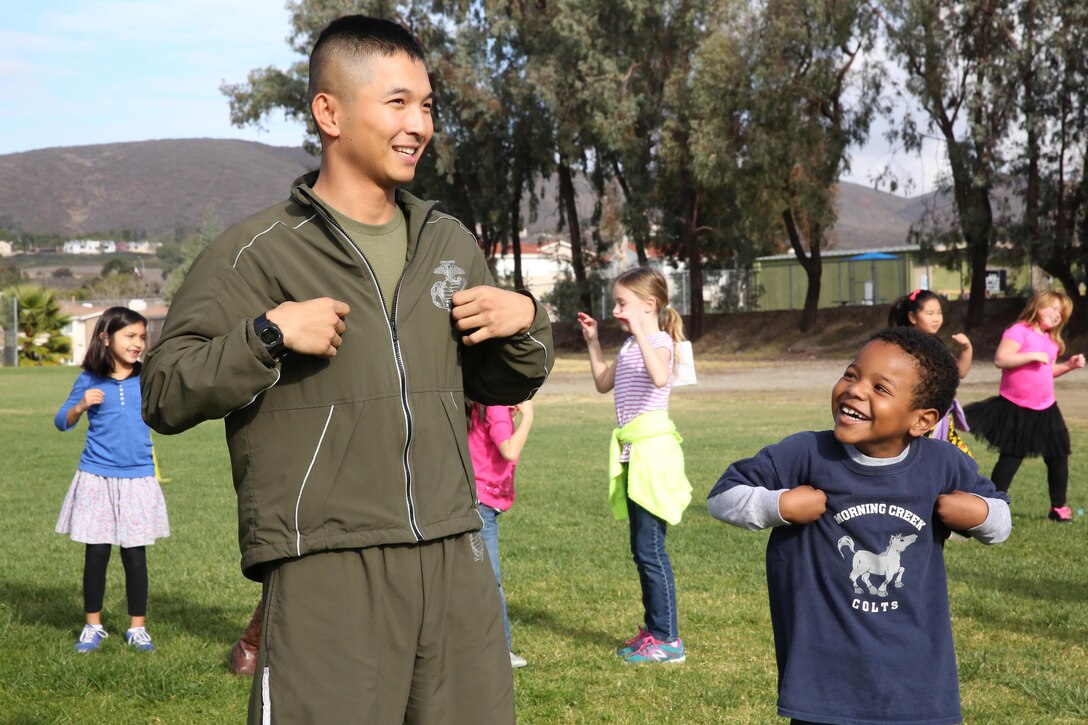 A Marine volunteer with Marine Aviation Logistics Squadron (MALS) 16, 3rd Marine Aircraft Wing, does the “Chicken Dance” with a Morning Creek Elementary School student during an annual Jog-a-Thon at Morning Creek Elementary School, San Diego, Feb. 6. More than 20 Marines led approximately 800 preschool through fifth-graders in stretching exercises and the “Chicken Dance” before running laps around the playground.