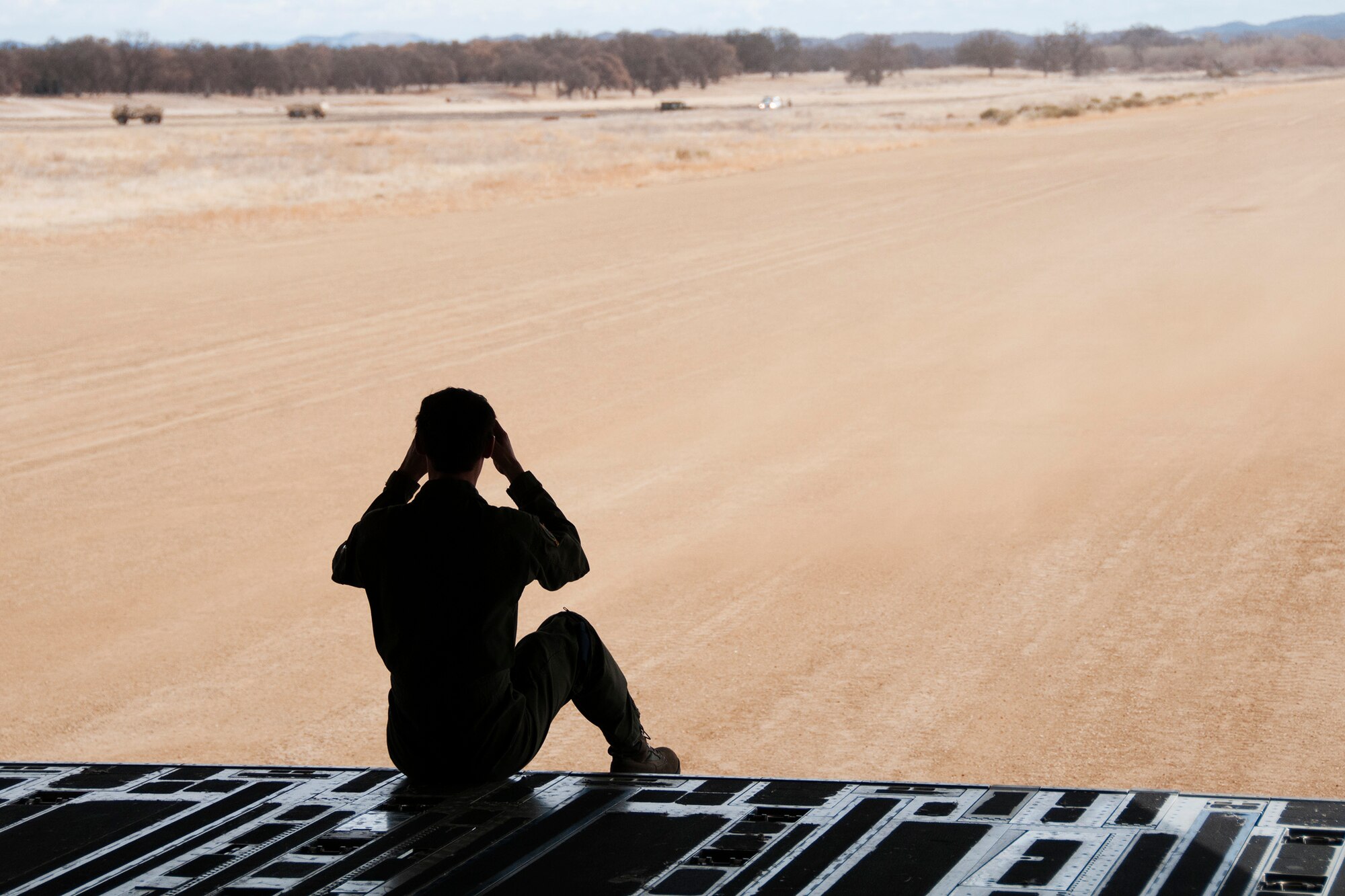 A loadmaster from the 728th Airlift Squadron, McChord Field, Wash., surveys the Semi-Prepared Runway [dirt landing strip] while aboard a McChord C-17 Globemaster III aircraft at Fort Hunter-Liggett, Calif., Jan. 31. The C-17 and the crew were there in support of an Air Force and Army live-fire operation. (U.S. Air Force photo by Jake Chappelle)