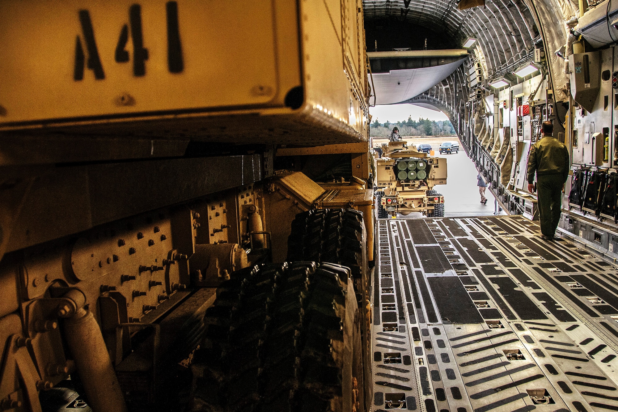 A loadmaster from the 728th Airlift Squadron at McChord Field, Wash., directs the second of two M142 High Mobility Artillery Rocket Systems from 17th Fires Brigade onto a C-17 Globemaster III aircraft, Jan. 31. The loading was part of an Air Force and Army operation to test fire the HIMARS at Fort Hunter-Liggett, Calif. (U.S. Air Force photo by Jake Chappelle)