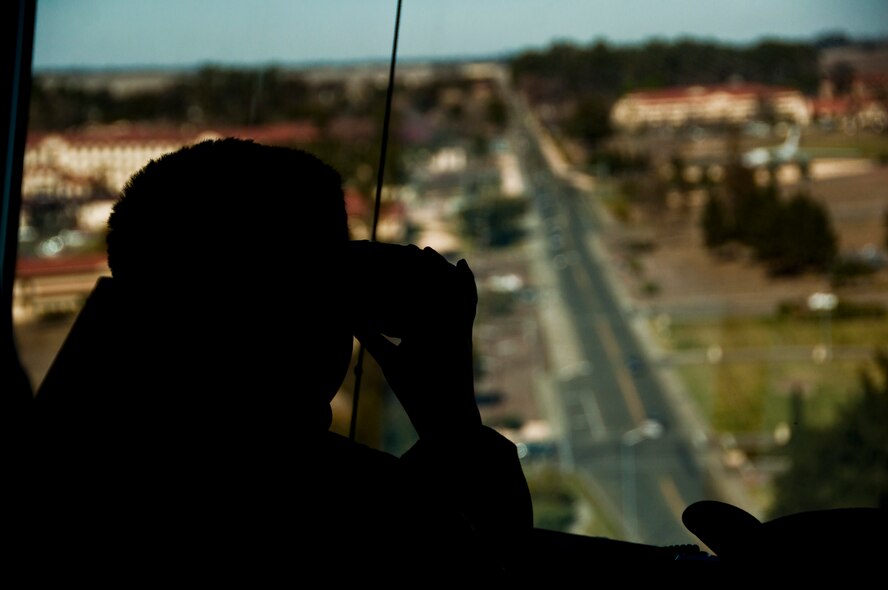 AJ Calisi surveys Travis Air Force Base from the air traffic control tower through binoculars provided to him by the Travis air traffic controllers. (U.S . Air Force photo/Senior Airman Madelyn Brown)