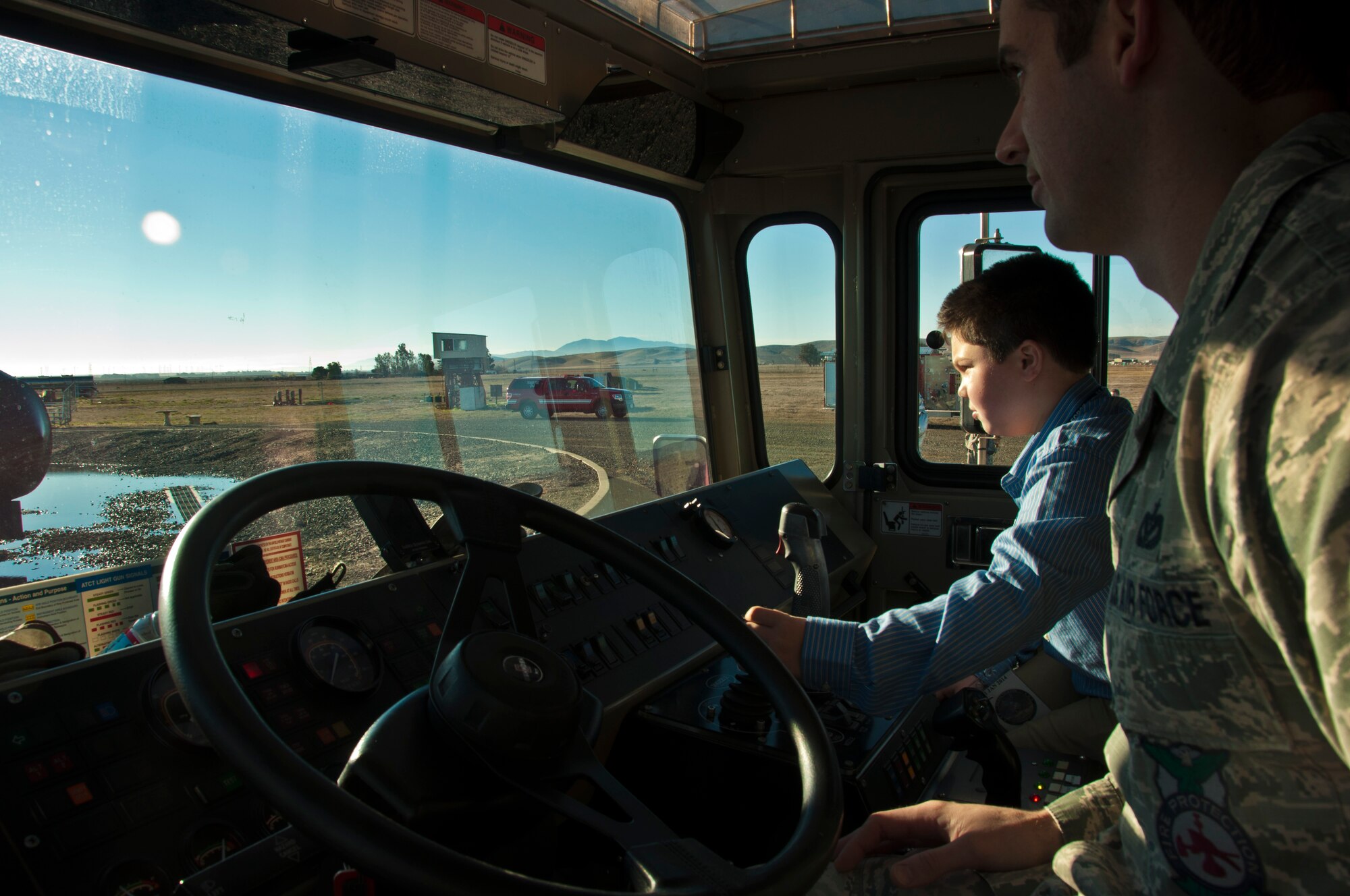 AJ Calisi, the honorary aircraft commander, learns the controls on a Travis fire truck prior to extinguishing a fire in an aircraft Jan. 31 through the Pilot for a Day and Make A Wish programs. (U.S. Air Force photo/Senior Airman Madelyn Brown)