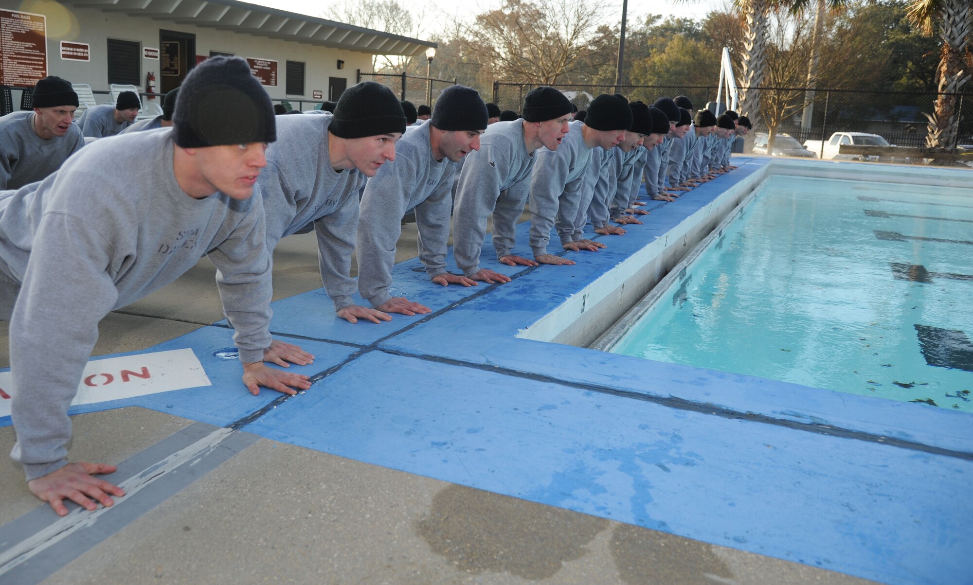 Combat Control Airmen from the 334th Training Squadron, conduct memorial push-ups to pay respect to fallen comrades following the heated triangle pool ribbon cutting ceremony Feb. 7, 2014, at Keesler Air Force Base, Miss. The heated pool will allow Keesler’s battlefield Airmen students the ability to execute water skills training without impeding on the limited time the students have in the morning for physical training before starting their academic day.   Prior to the heater being installed, the Airmen had to use an off base facility.  (U.S. Air Force photo by Kemberly Groue)