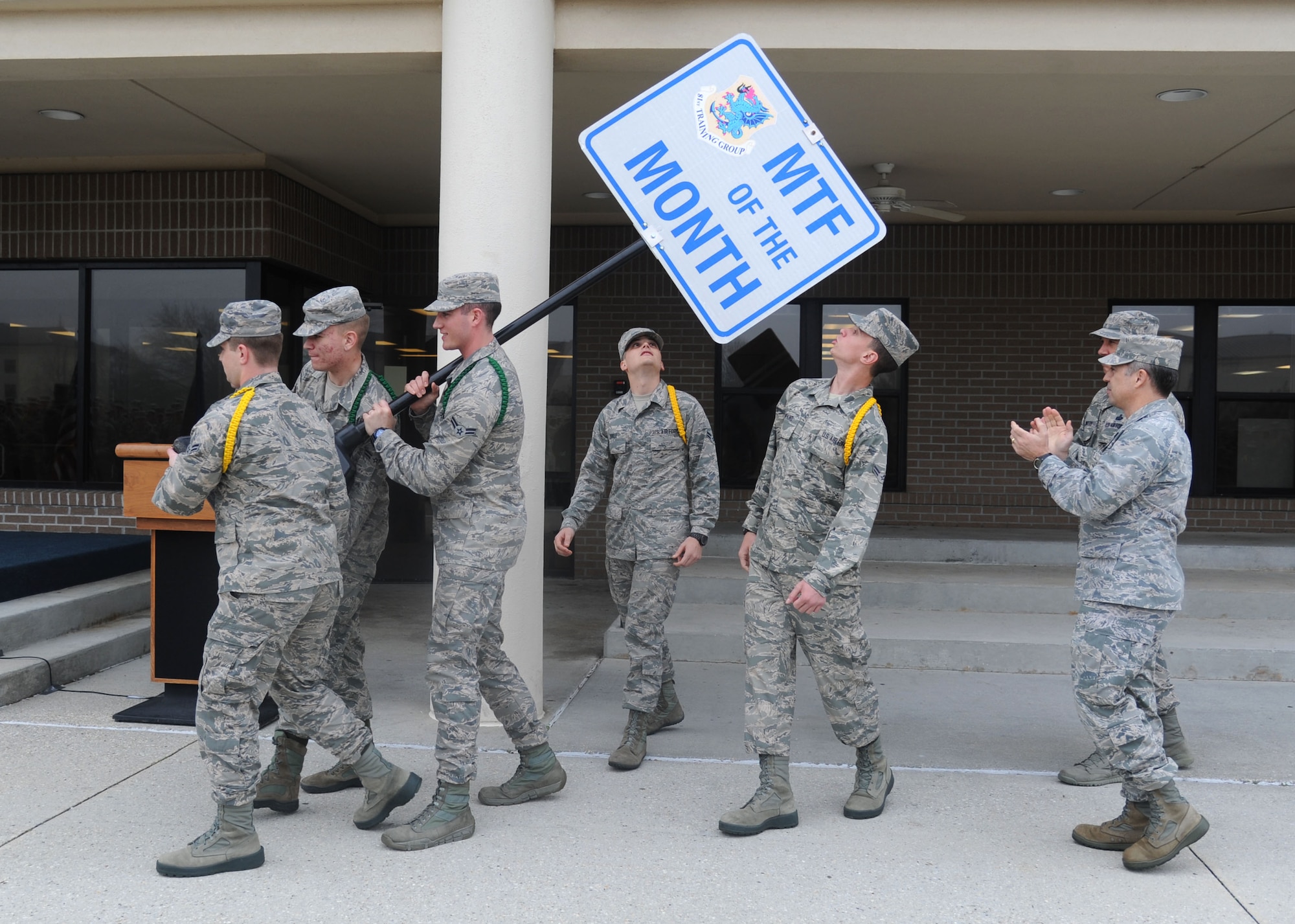 Col. George Tombe IV, 81st Training Group commander, and Chief Master Sgt. Robert Winters, 81st TRG superintendent, applaud as a group of Airmen from the 336th Training Squadron carry the Military Training Flight of the Month sign Feb. 4, 2014, at the Levitow Training Support Facility, Keesler Air Force Base, Miss., after the squadron was recognized as the Military Training Flight of the Month for January. The 336th TRS was also recognized as 81st Training Wing Technical Training Squadron of the Year for 2013.  (U.S. Air Force photo by Kemberly Groue)
