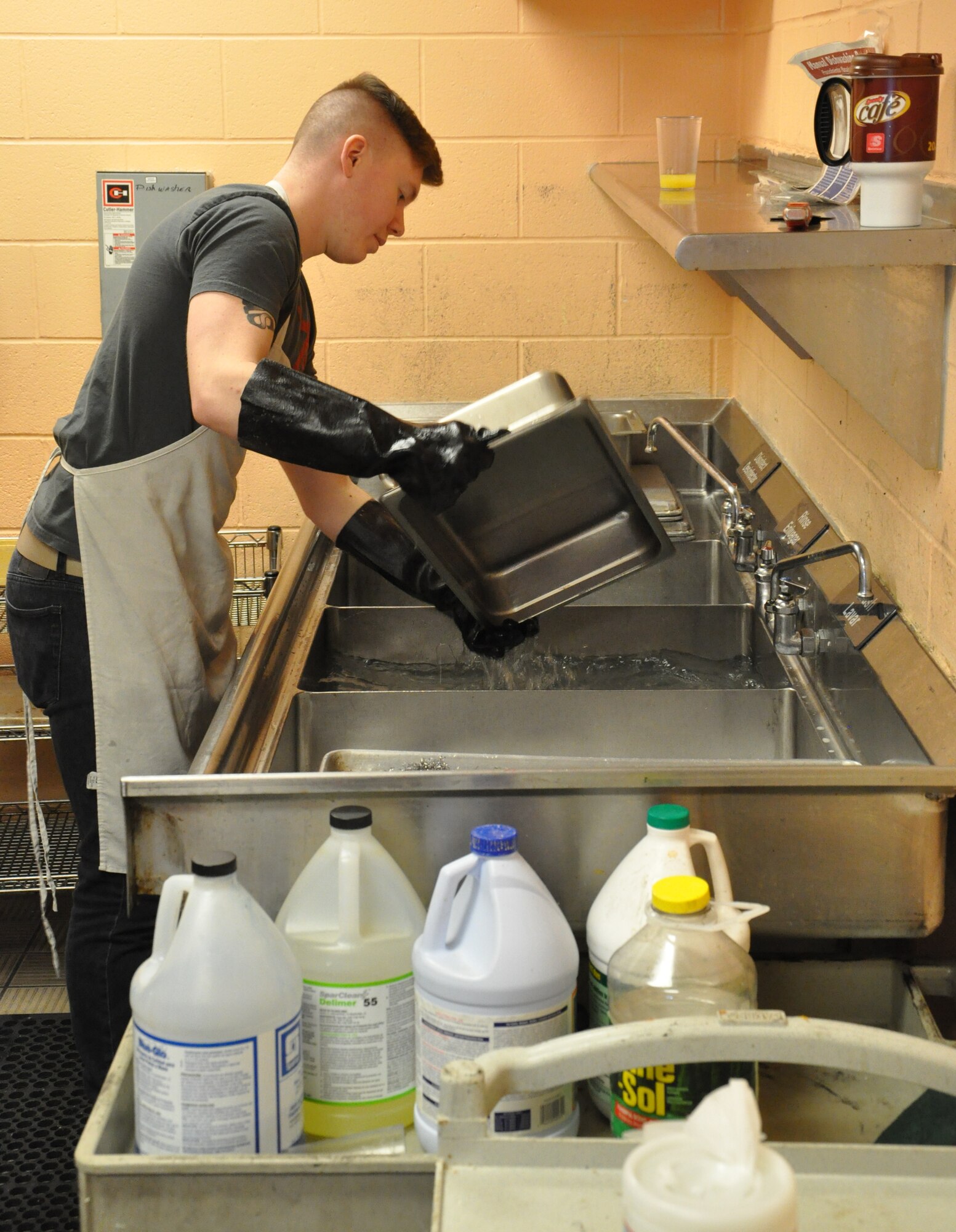 Senior Airman Ian Hooper from National Air and Space Intelligence Center scrubs to clean pans at the House of Bread in Dayton, Ohio, where he volunteered to help the community kitchen to prepare, server and clean the kitchen with nine other Airmen from Wright-Patterson AFB. (USAF photo by Ted Theopolos).