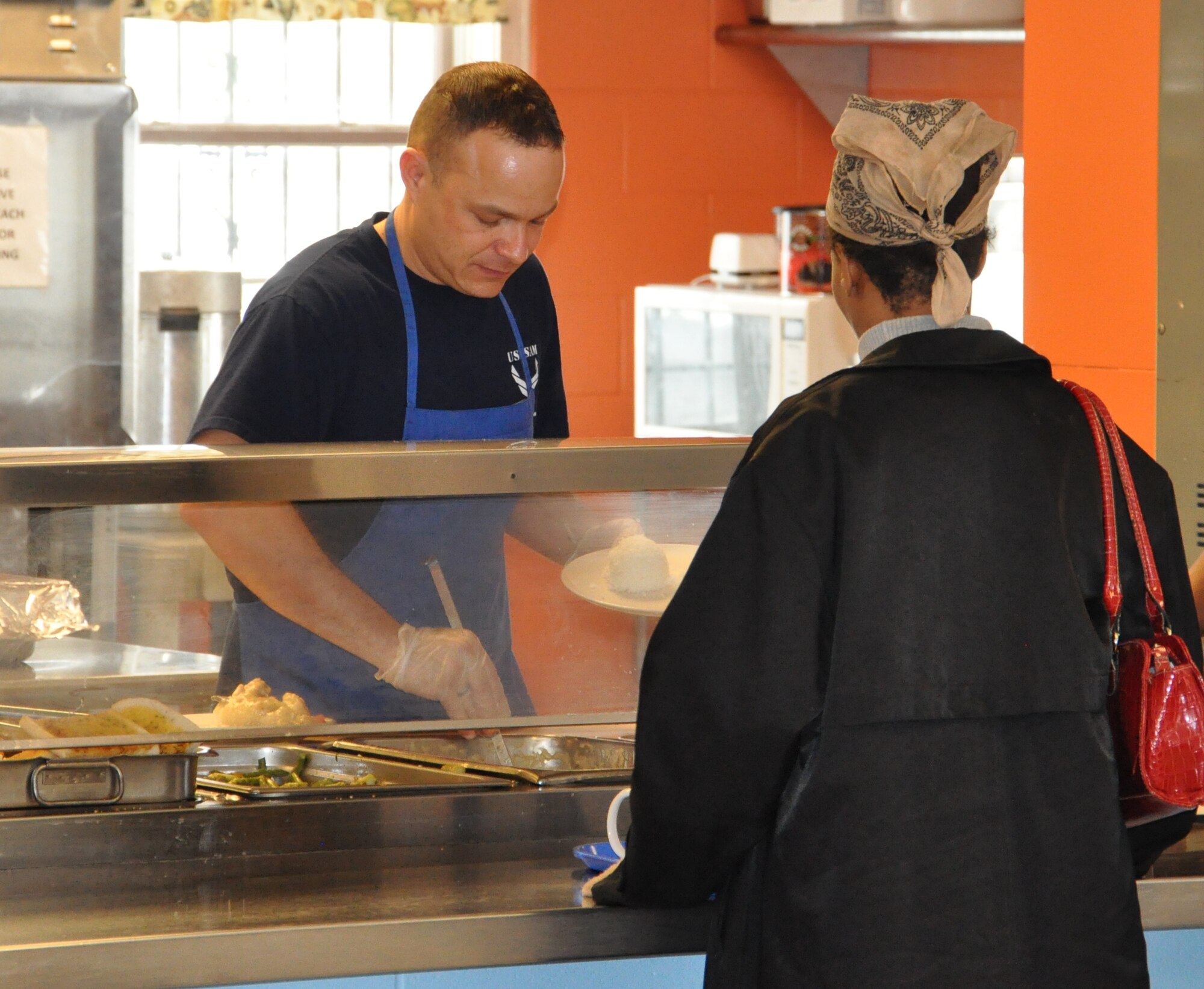 Tech.  Sgt. Michael Stegen from U.S. Air Force School of Aerospace Medicine, dishes out food to serve a visitor at the House of Bread in Dayton, Ohio.  Stegen was one of 10 Airmen from Wright-Patterson AFB who volunteered to help the community kitchen serve lunch. (USAF photo by Ted Theopolos) 