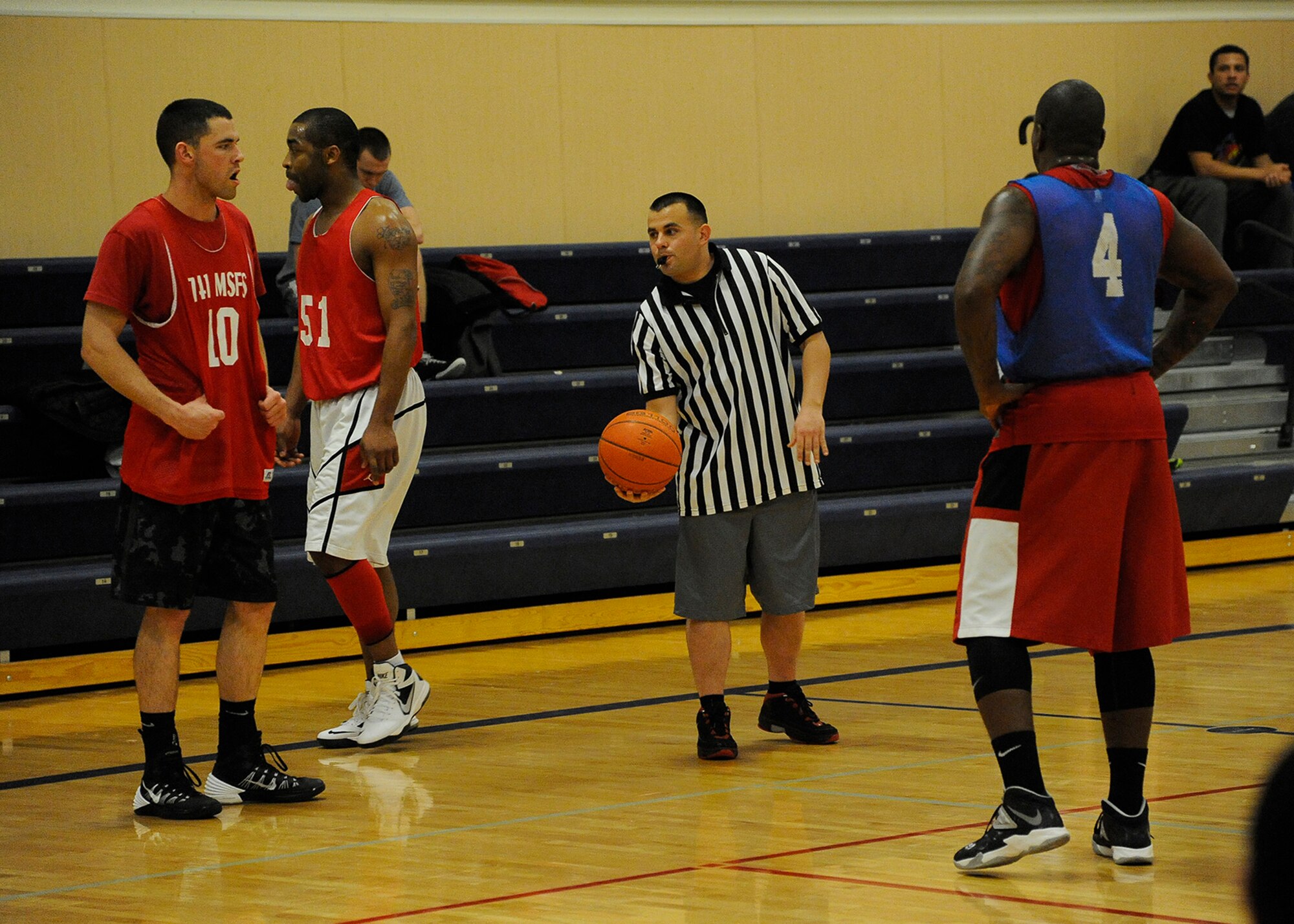 Staff Sgt. Nicholas Capriato, 341st Security Forces Squadron remote target engagement system operator (center) hands the ball to Senior Airman Collin Reber, 741st Missile Security Forces Squadron member (far left) to put the ball in play during the 2013 season Championship game Feb. 3. After his team was knocked out of the running for the championship, Capriato continued to volunteer his time as a referee for the basketball games – a much needed help, according to the fitness center’s sports director. (U.S. Air Force photo/Airman 1st Class Collin Schmidt)