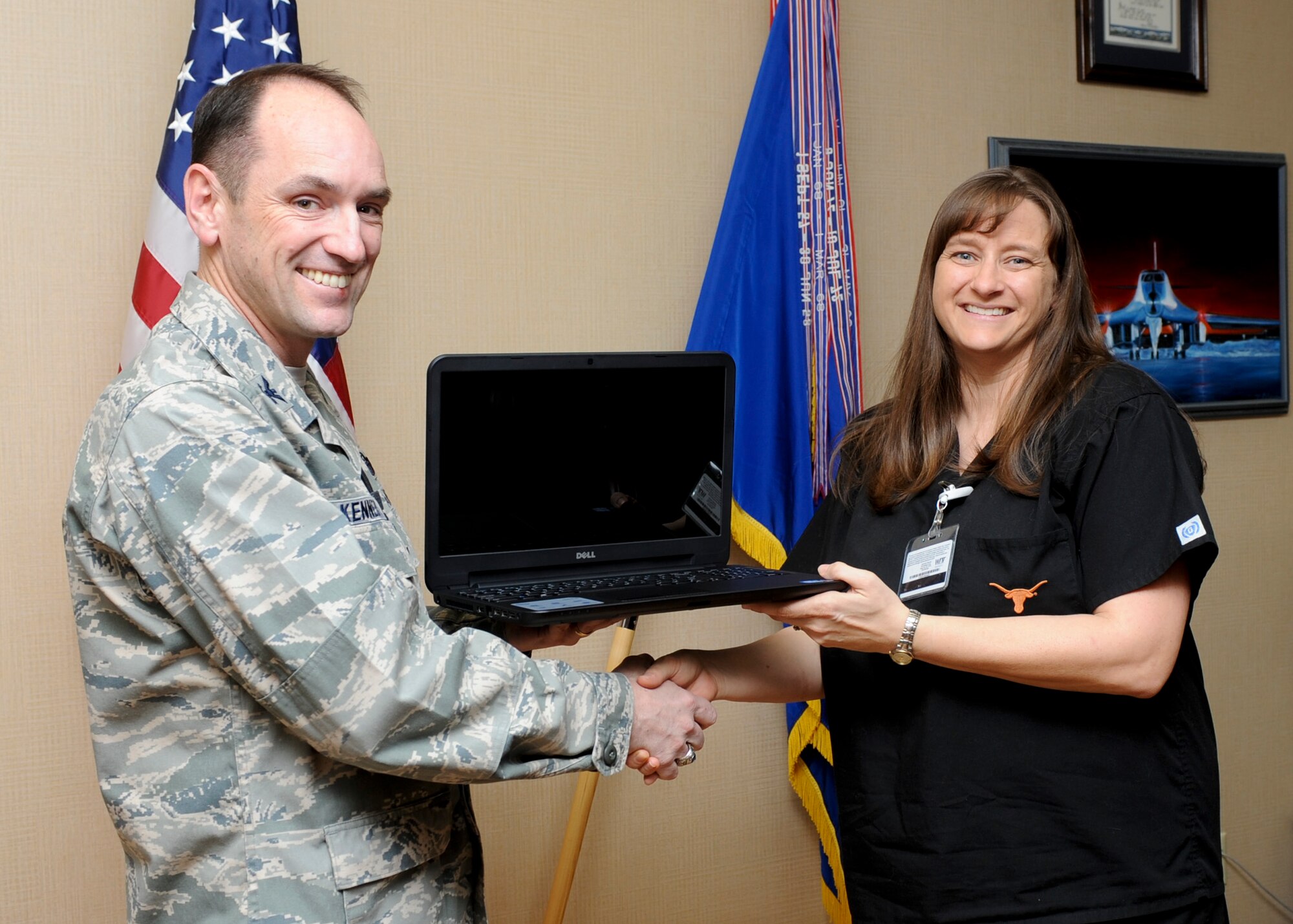 Col. Kevin Kennedy, 28th Bomb Wing commander, presents April Collins, wife of Master Sgt. Joe Collins, 28th Security Forces Squadron combat arms section chief, with a new laptop at Ellsworth Air Force Base, S.D., Feb. 3, 2014. Collins was one of 25 people awarded a 2013 Air Force Club Membership Scholarship which, along with the laptop, included an inkjet printer and $1,000. Over the past 15 years, the AFCS Program has awarded $375,000 in college tuition to Air Force Club members and their families.  (U.S. Air Force photo by Senior Airman Anania Tekurio/Released)