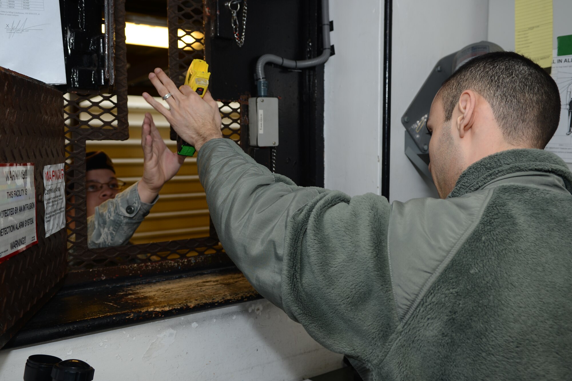 U.S. Air Force Staff Sgt. Joshua Garcia, right, 100th Security Forces Squadron armory NCO in charge from El Paso, Texas, hands a stun gun to a 100th SFS Airman Jan. 30, 2014, on RAF Mildenhall, England.  The armory is responsible for issuing weapons during shift change and maintaining the weapons inventory. The 100th SFS employs a range of weapons for different situations, including downrange operations and base defense. (U.S. Air Force photo by Airman 1st Class Dillon Johnston/Released)