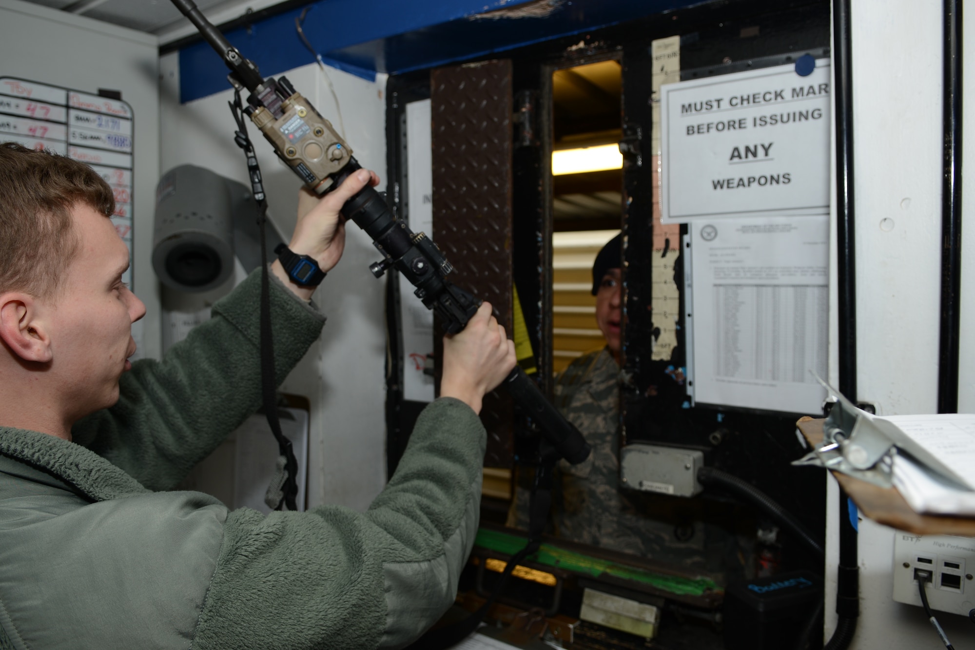 U.S. Air Force Airman 1st Class Joey Long, 100th Security Forces Squadron armory journeyman from Overland Park, Kan., hands an M4 carbine to a 100th SFS Airman Jan. 30, 2014, on RAF Mildenhall, England. The armory is responsible for issuing weapons during shift change and maintaining the weapons inventory. The 100th SFS employs a range of weapons for different situations, including downrange operations and base defense. (U.S. Air Force photo by Airman 1st Class Dillon Johnston/Released)