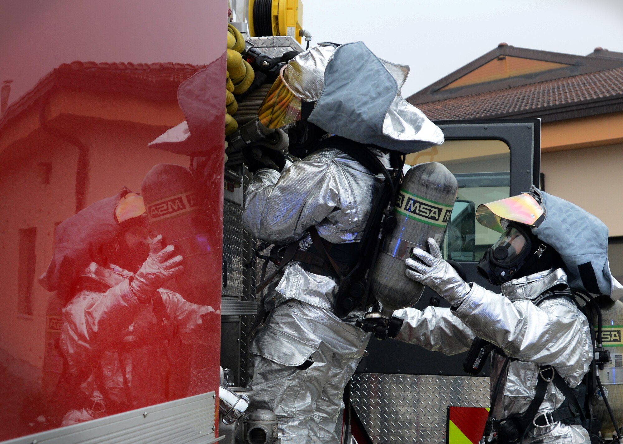 Two 31st Civil Engineer Squadron firefighters, unload a hose from a fire truck during a wing inspection, Feb. 5, 2014, at Aviano Air Base, Italy. The inspection’s scenarios tested the wing’s readiness and emergency standards. (U.S. Air Force photo/Airman 1st Class Deana Heitzman)