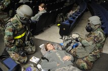 Tech. Sgt. Richard Moss, 8th Comptroller Squadron budget technician, and Senior Airman Troy Beadles, 8th Communications Squadron, perform self-aid and buddy care on an exercise role player during exercise Beverly Midnight 14-01 at the base theater on Kunsan Air Base, Republic of Korea, Feb. 7, 2014. This scenario allowed the Wolf Pack to demonstrate their ability to respond to a mass casualty situation and aid Airmen needing medical attention. (U.S. Air Force photo by Staff Sgt. Jessica Haas/Released) 