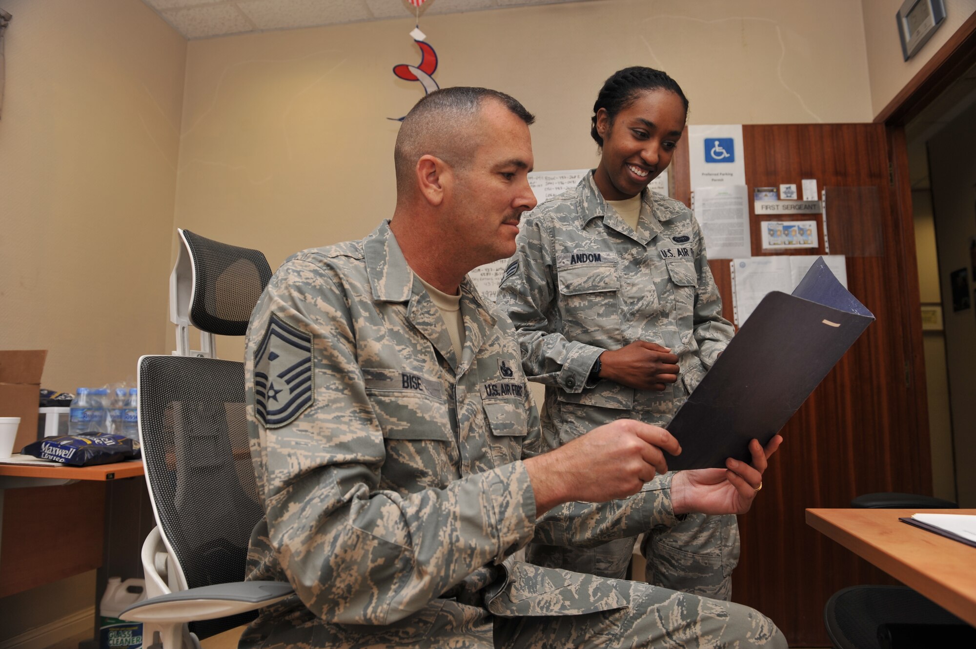 Senior Master Sgt. Jeffrey Bise reviews a document with Senior Airman Mary Andom at the 379th Expeditionary Maintenance Squadron, Al Udeid Air Base, Qatar, Feb. 5, 2014. Andom received a $125 scholarship from the Al Udeid Air Base Air Force Sergeants Association, Gran Slam Lite Chapter, to continue her advanced education. Andom is a 379th EAMXS knowledge operations management journeyman deployed from Spangdahlem Air Base, Germany and a Seattle native. Bise is one of two of the 379th EAMXS First Sergeants and is deployed from Ramstein Air Base, Germany and a Honaker, Va., native. 