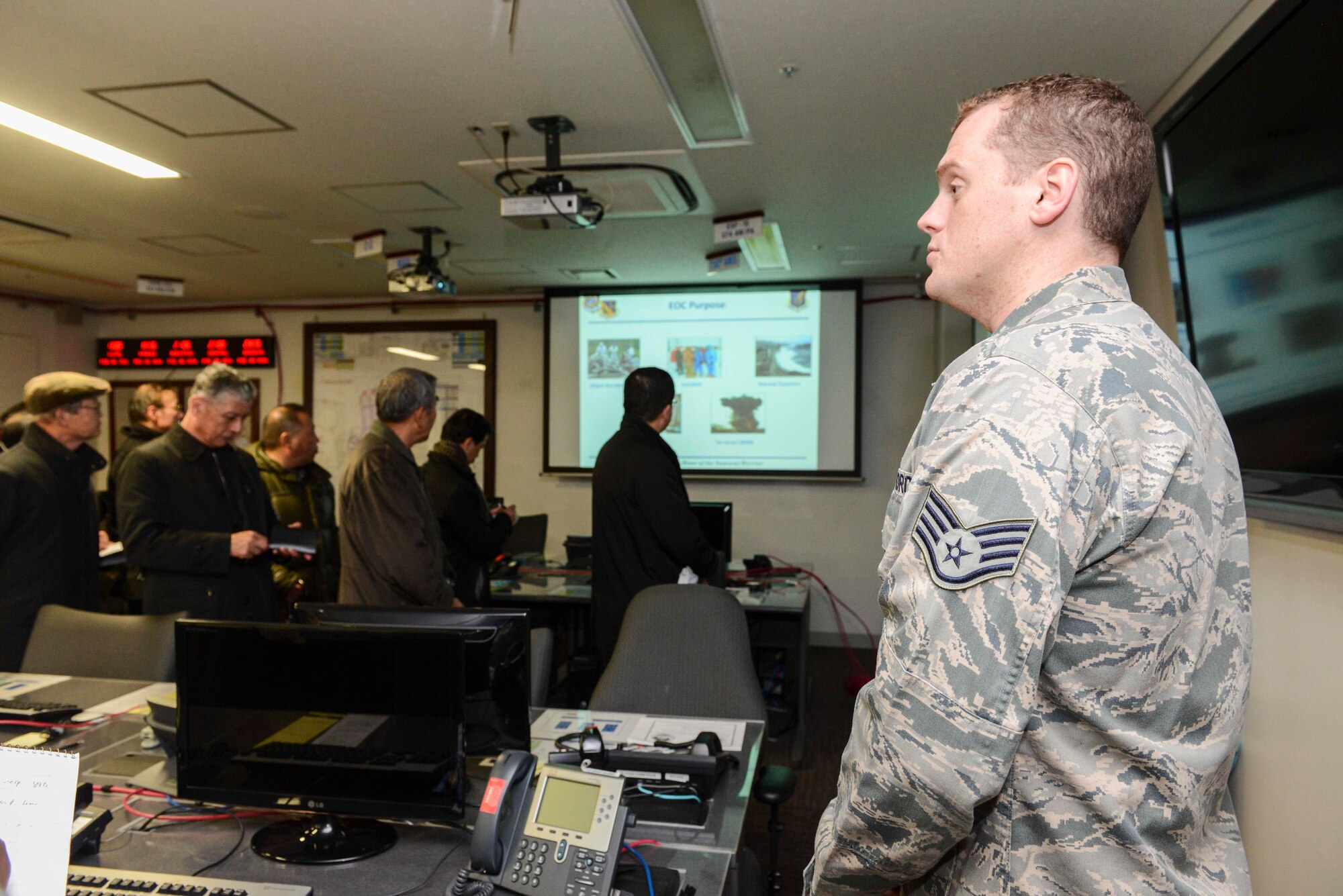 Staff Sgt. Timothy Lyons, 374th Civil Engineering Squadron non-commissioned officer in charge of plans and operations, gives a briefing on the functions of emergency operation center at Yokota Air Base, Japan, Feb. 4, 2014.  Members of the Japan Society for Security and Crisis Management visited Yokota to gain deeper understanding of Yokota’s disaster response capability and crisis management system.  (U.S. Air Force photo by Airman 1st Class Soo C. Kim / released)