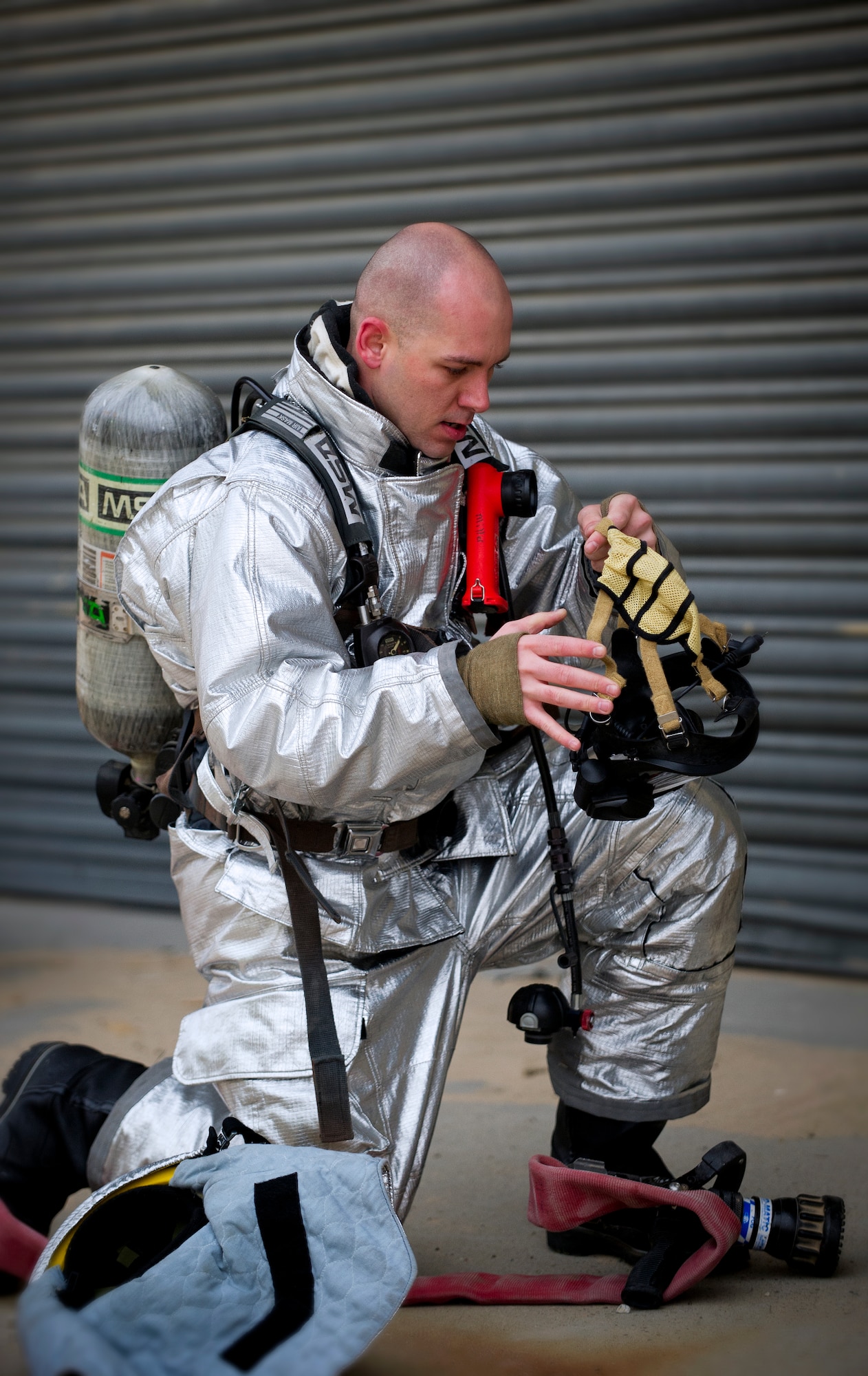Firefighter Airman Justin Lillard, 386th Expeditionary Civil Engineer Squadron, prepares to don his respirator during while responding to a simulated fire during a training event between the Fire Department and the 386th Expeditionary Medical Squadron on Feb. 2.  The training between the two squadrons enhances the first responders ability to react to actual emergency situations.  (U.S. Air Force photo by Senior Master Sgt. Burke Baker) 
