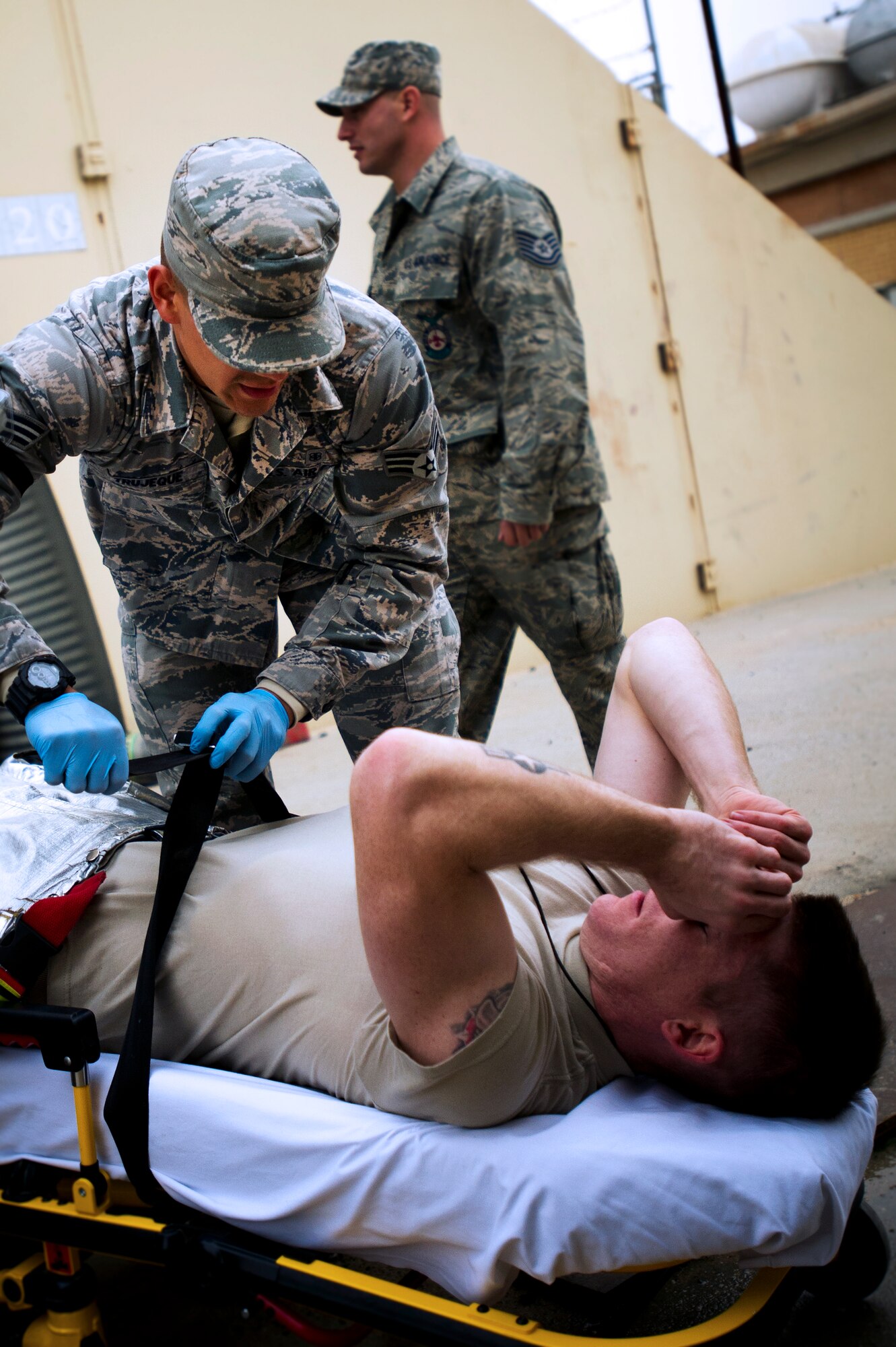 Firefighter Staff Sgt. Jason Reed, 386th Expeditionary Civil Engineer Squadron, acts as a patient during a training event between the Fire Department and the 386th Expeditionary Medical Squadron on Feb. 2.  Reed is being prepared for transport by first responder Senior Airman Enrique Trujeque (left), 386th EMEDS for further treatment. (U.S. Air Force photo by Senior Master Sgt. Burke Baker) 