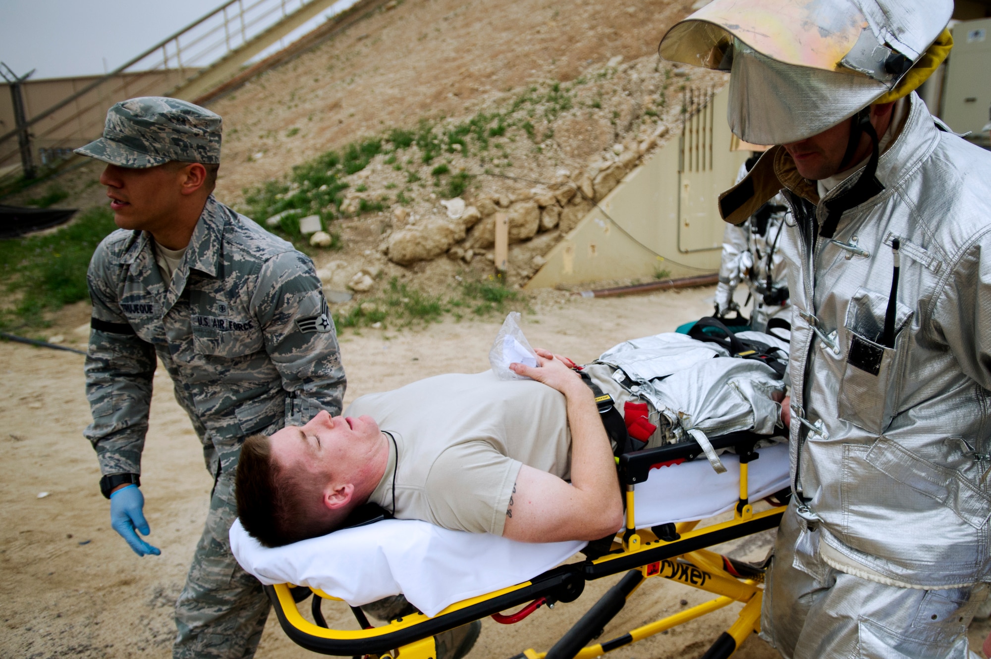 Firefighter Staff Sgt. Jason Reed, 386th Expeditionary Civil Engineer Squadron, acts as a patient during a training event between the Fire Department and the 386th Expeditionary Medical Squadron on Feb. 2.  Reed is being transported to an ambulance by first responders Senior Airman Enrique Trujeque (left), 386th EMEDS, and Staff Sergeant Jacob Harris, 386th ECES for further treatment. (U.S. Air Force photo by Senior Master Sgt. Burke Baker) 