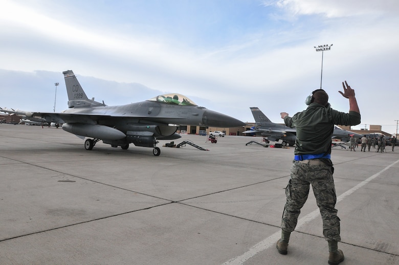 U.S. Air National Guard Airman First Class Tyler Garrod, 140th Maintenance Squadron, Colorado Air National Guard, ushers out an F-16 Fighting Falcon fighter jet from the 120th Fighter Squadron at Buckley Air Force Base, Colo., to taxi before a training mission at Red Flag 14-1, at Nellis Air Force Base, Nev., Jan. 30, 2014. Combat units come together from the United States and its allied countries to engage in realistic combat training scenarios within Nellis’ 2.9 million acre Test and Training Range Complex. (U.S. Air National Guard photo/Tech. Sgt. Wolfram M. Stumpf)