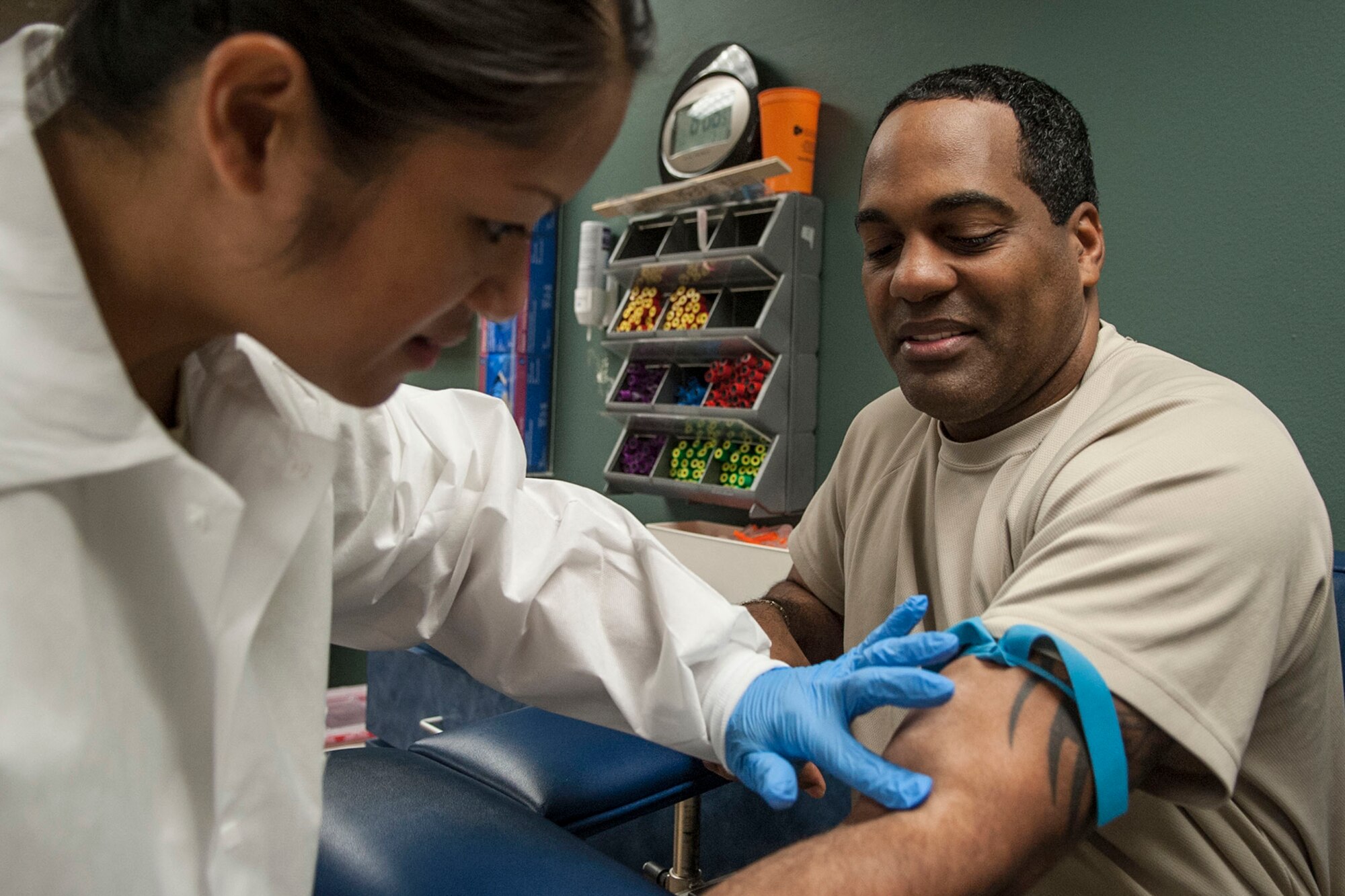 U.S. Air Force Tech. Sgt. Anthony Faulcon, 307th Bomb Wing human resources manager, , waits patiently as Staff Sgt. Darren Paris, 307th Medical Squadron lab technician, searches for a vein at Barksdale Air Force Base, La., Feb. 8, 2014. (U.S. Air Force photo by Master Sgt. Jeff Walston/Released) 