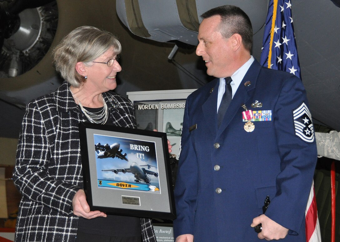 Margaret Whitman, administrative assistant to 512th Airlift Wing commander, presents 512th Airlift Wing Command Chief Master Sgt. William T. Wild III with a token of appreciation on behalf of the 512th AW staff during Wild's official retirement ceremony at the Air Mobility Command Museum, Dover, Del., Feb. 8, 2014. (U.S. Air Force photo/Senior Airman Erika Brooke)