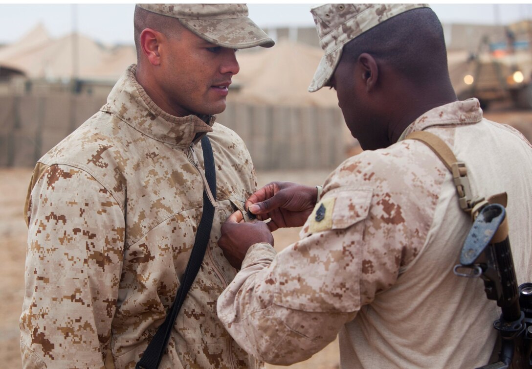 Sergeant Marcus Myers, a food service specialist with Headquarters Company, 1st Battalion, 9th Marine Regiment, Regional Command (Southwest), has his new rank pinned by Staff Sgt. Aviel Smith, food service specialist chief, Headquarters Co., aboard Patrol Base Boldak in Helmand province, Afghanistan, Feb. 2, 2014. Myers was meritoriously promoted to the rank of sergeant and received a Navy and Marine Corps Achievement Medal after his outstanding service was recognized by Gen. James F. Amos, commandant of the Marine Corps. (U.S. Marine Corps photo by Cpl. Cody Haas/ Released)