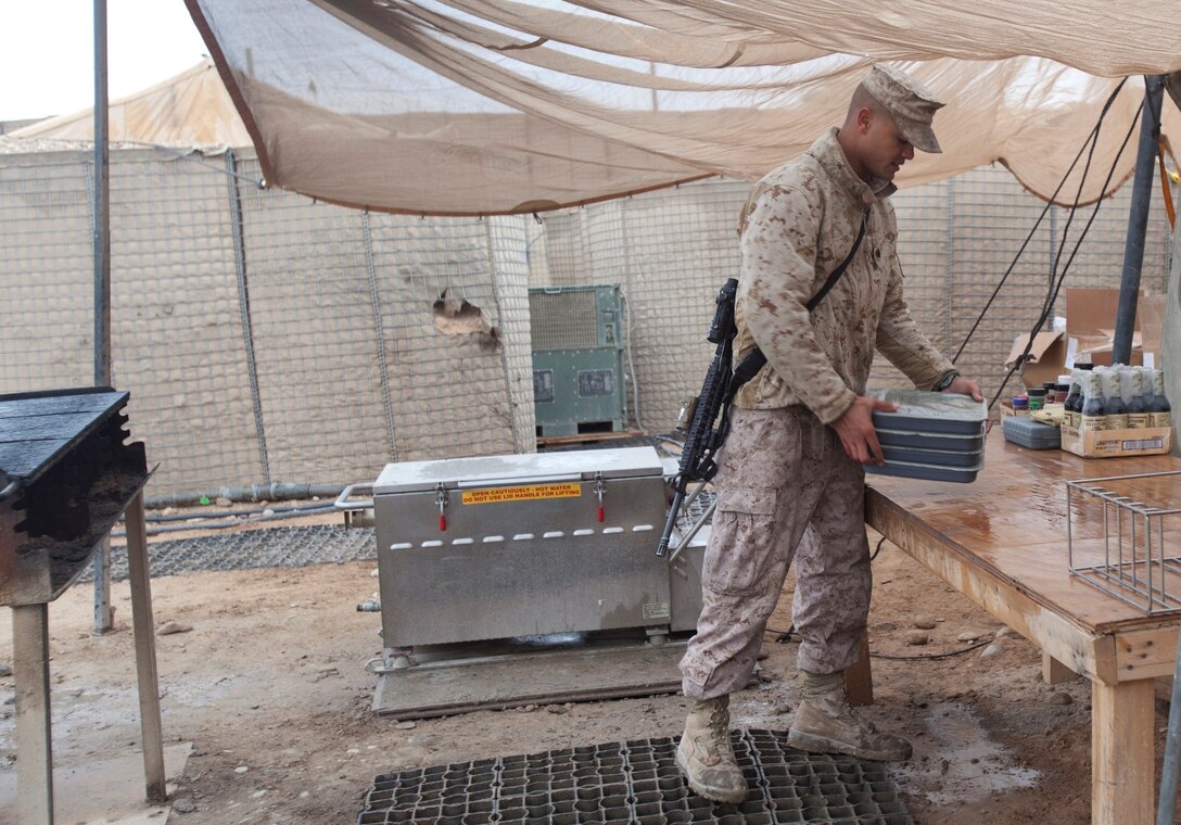 Sergeant Marcus Myers, a food service specialist with Headquarters Company, 1st Battalion, 9th Marine Regiment, Regional Command (Southwest), carries pans of spaghetti he prepared for troops aboard Patrol Base Boldak in Helmand province, Afghanistan, Feb. 2, 2014. Myers was meritoriously promoted to the rank of sergeant and received a Navy and Marine Corps Achievement Medal after his outstanding service was recognized by Gen. James F. Amos, commandant of the Marine Corps. (U.S. Marine Corps photo by Cpl. Cody Haas/ Released)
