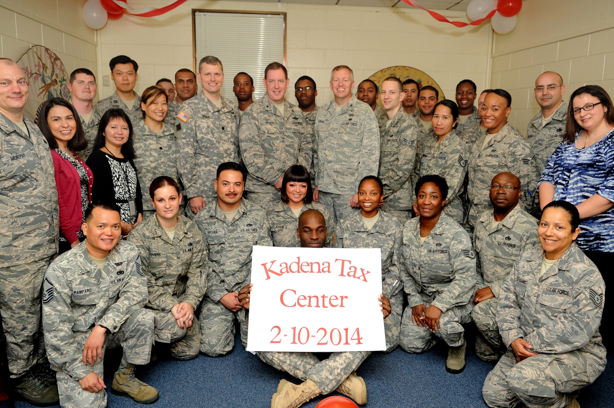 U.S. Army Lt. Col. Benjamin Ogden (top middle left), 1st Battalion, 1st Air Defense Artillery Regiment battalion commander, U.S. Air Force Brig. Gen. James Hecker (middle), 18th Wing commander, and Col. Edward Lucas (top middle right), 18th Wing Legal Office staff judge advocate, pose for a group photo with volunteers from the Kadena tax center during the grand opening ceremony on Kadena Air Base, Japan, Feb. 10, 2014. The tax center is operated by more than 30 certified volunteer income tax assistance representatives who will provide free electronic tax filing to all Department of Defense ID card holders. (U.S. Air Force photo by Staff Sgt. Amber E. N. Jacobs)
