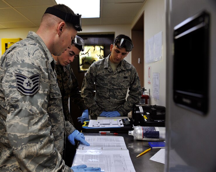 U.S. Air Force Tech. Sgt. Richard Crom, 18th Logistics Readiness Squadron NCO in charge of fuel lab, shows technical orders to U.S. Marine Corps Cpl. Daniel Ramirez, 9th Engineer Support Battalion bulk fuel technician, and U.S. Air Force Airman 1st Class Erran Gates, 18th Logistics Readiness Squadron fuels distribution operator, during a Field Exchange Program on Kadena Air Base, Japan, Feb. 6, 2014. During the trial program, Marines rotate into Air Force operations six months to educate Marine bulk refueling technicians on airfield procedures to include receipt, transfer, lab analysis and issuance of aviation fuels. (U.S. Air Force photo by Naoto Anazawa)