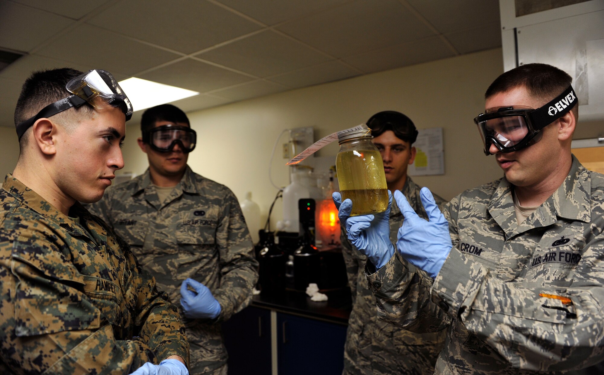U.S. Air Force Tech. Sgt. Richard Crom, 18th Logistics Readiness Squadron NCO in charge of fuel lab, presents a container of a fuel and water mixture during a Field Exchange Program on Kadena Air Base, Japan, Feb. 6, 2014. The Field Exchange Program is the first of its kind which combines the Air Force and Marine Corps training on fuel procedures. (U.S. Air Force photo by Naoto Anazawa)