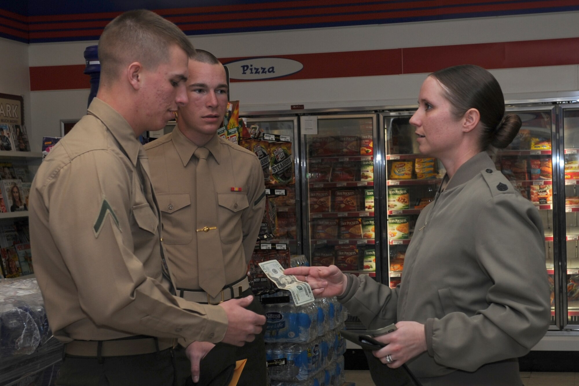 GOODFELLOW AIR FORCE BASE, Texas -- Marine Corps Staff Sgt. Brennan Rivera-Jones, Marine Corps Detachment operations chief, gives Marine Corps Pfcs. Steven Dugan and Michael Skoworn, MCD students, $20 each at the shoppette Jan. 17. Rivera-Jones handed out the cash along with other first sergeants from the base as a Random Acts of Kindness event to junior enlisted members. (U.S. Air Force photo/ Staff Sgt. Laura R. McFarlane)