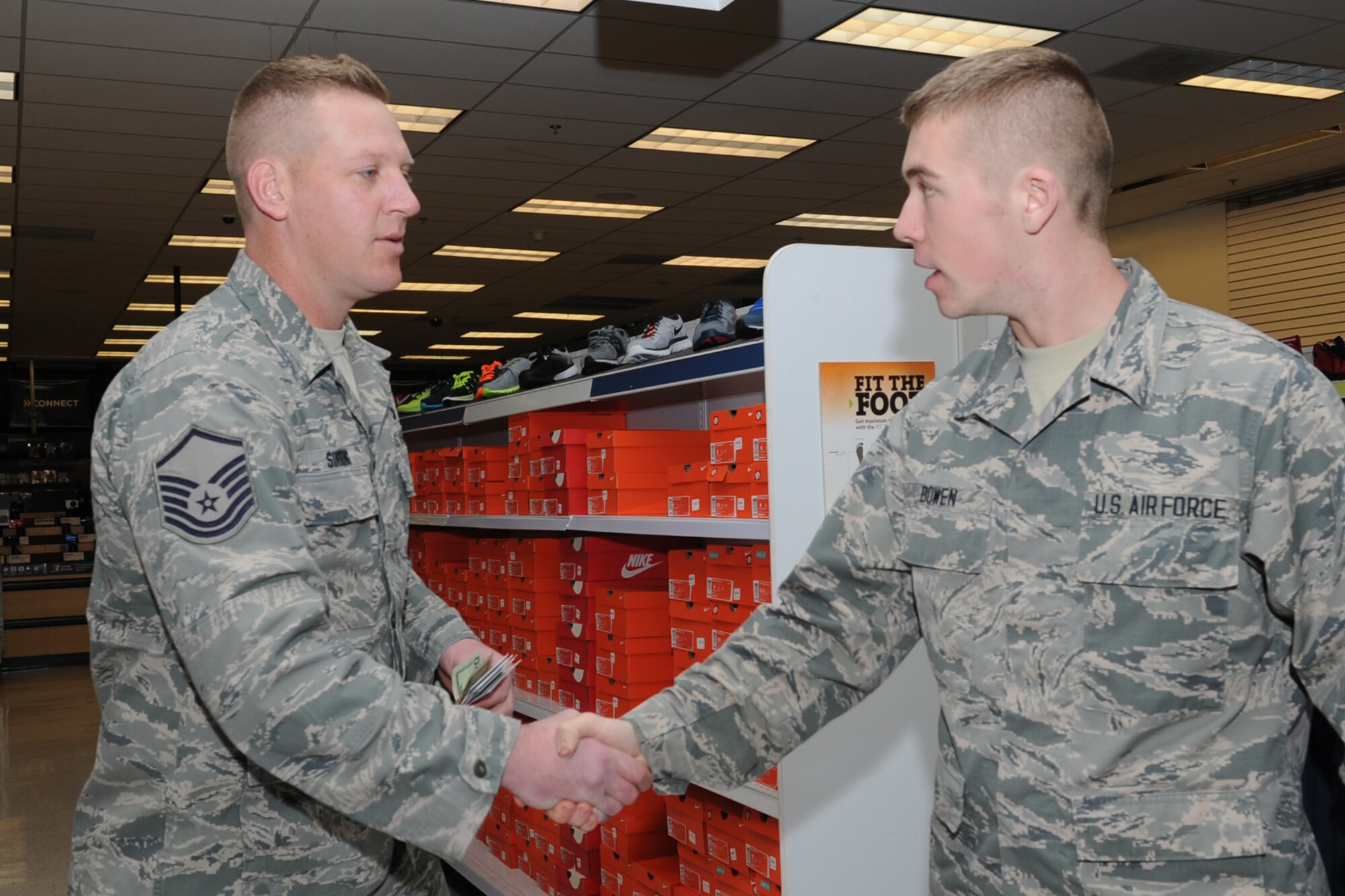 GOODFELLOW AIR FORCE BASE, Texas -- Master Sgt. Nathan Sinning, 17th Security Forces Squadron first sergeant, surprises Airman 1st Class Joseph Bowan, 312th Training Squadron student, with a $20 gift card at the Base Exchange Jan. 17. First sergeants from several squadrons presented cards and cash to unsuspecting service members. (U.S. Air Force photo/ Staff Sgt. Laura R. McFarlane)