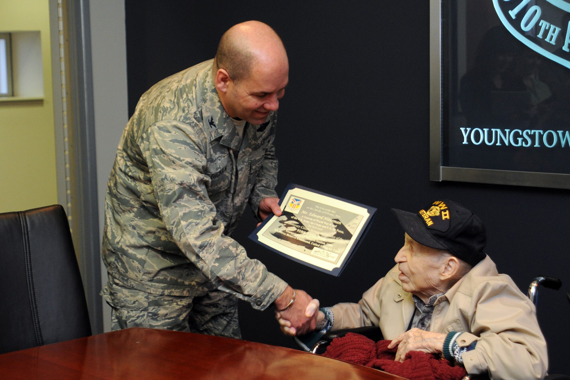 YOUNGSTOWN AIR RESERVE STATION, Ohio – Air Force Reserve Col. James Dignan, 910th Airlift Wing commander, presents a certificate to Mr. Edward Hitesman, a World War II Army Air Corps veteran, during a special tour here, Feb. 2, 2014. The certificate named the veteran an honorary member of the 910th Airlift Wing. Hitesman and his family visited YARS at the request of Crossroads Hospice in Green, Ohio as part of the facility’s Gift of a Day program. The program is designed to ask terminal patients, “How do you envision your perfect day?” The hospice then strives to create that image and make it a special day for the patient and their family. The 94-year-old veteran’s idea of a “perfect day” was to spend it at YARS and with the Citizen Airmen of the 910th Airlift Wing. U.S. Air Force photo by Senior Airman Rachel Kocin.