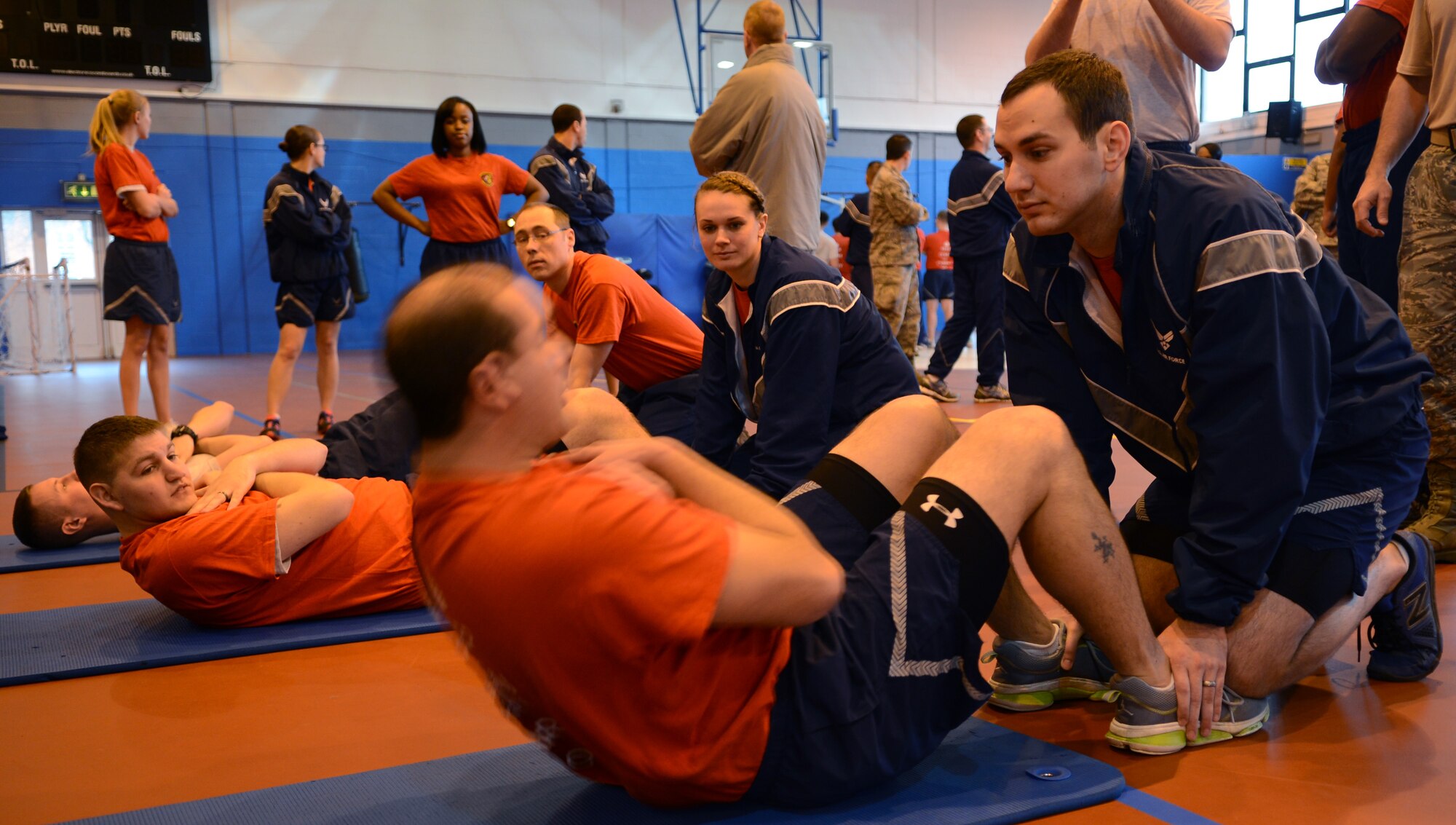 100th Communications Squadron members participate in a situp competition Feb. 7, 2014, during the Northside Fitness Center sports day on RAF Mildenhall, England. The 100th CS competed against the 100th Force Support Squadron in both a situp and pushup competition. The 100th FSS won both, performing more than 800 situps and pushups. (U.S. Air Force photo by Airman 1st Class Dillon Johnston/Released)